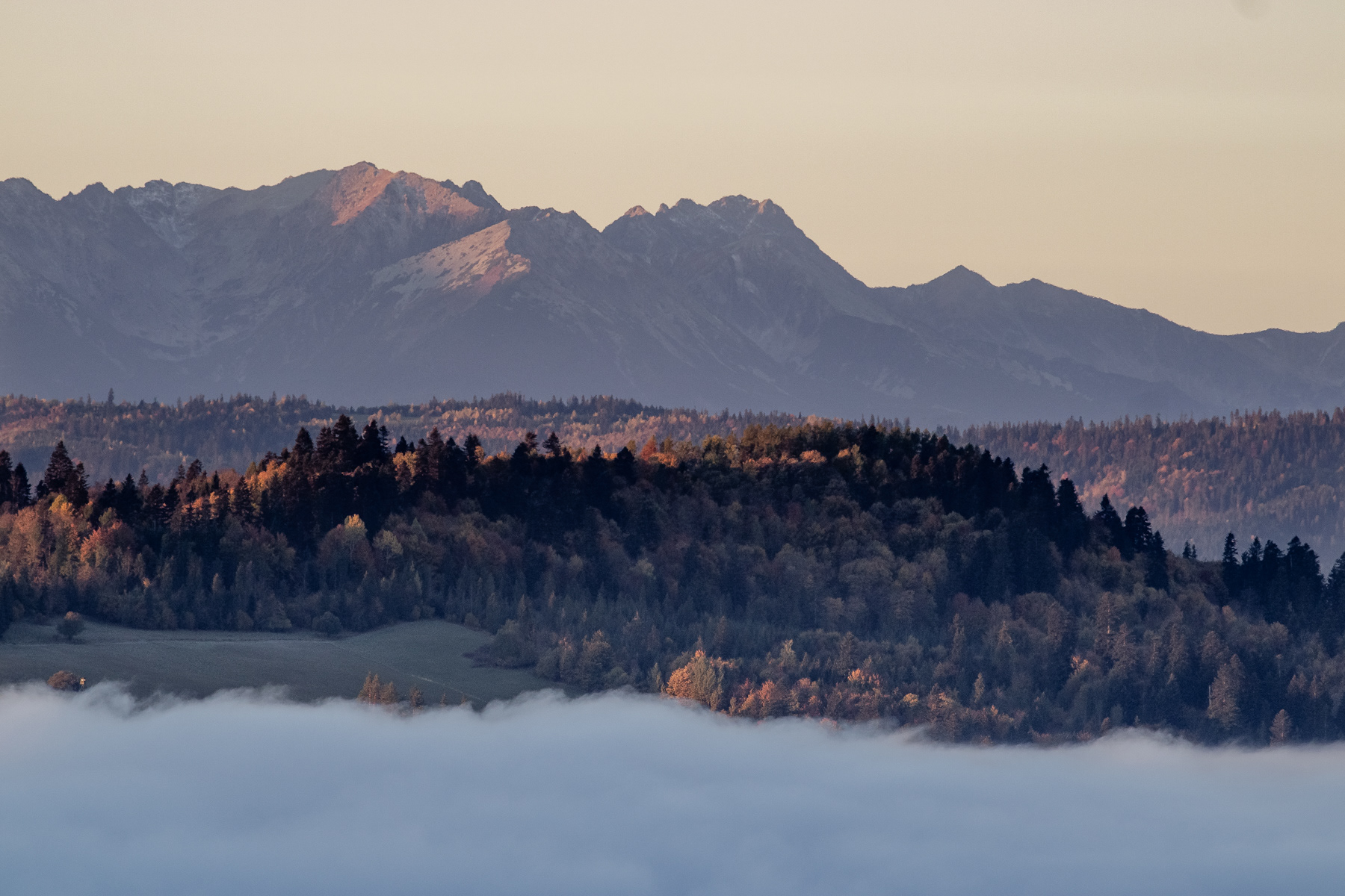 The warm sunlight catches the contours of the Tatras and the tree covered lower hills north of it.