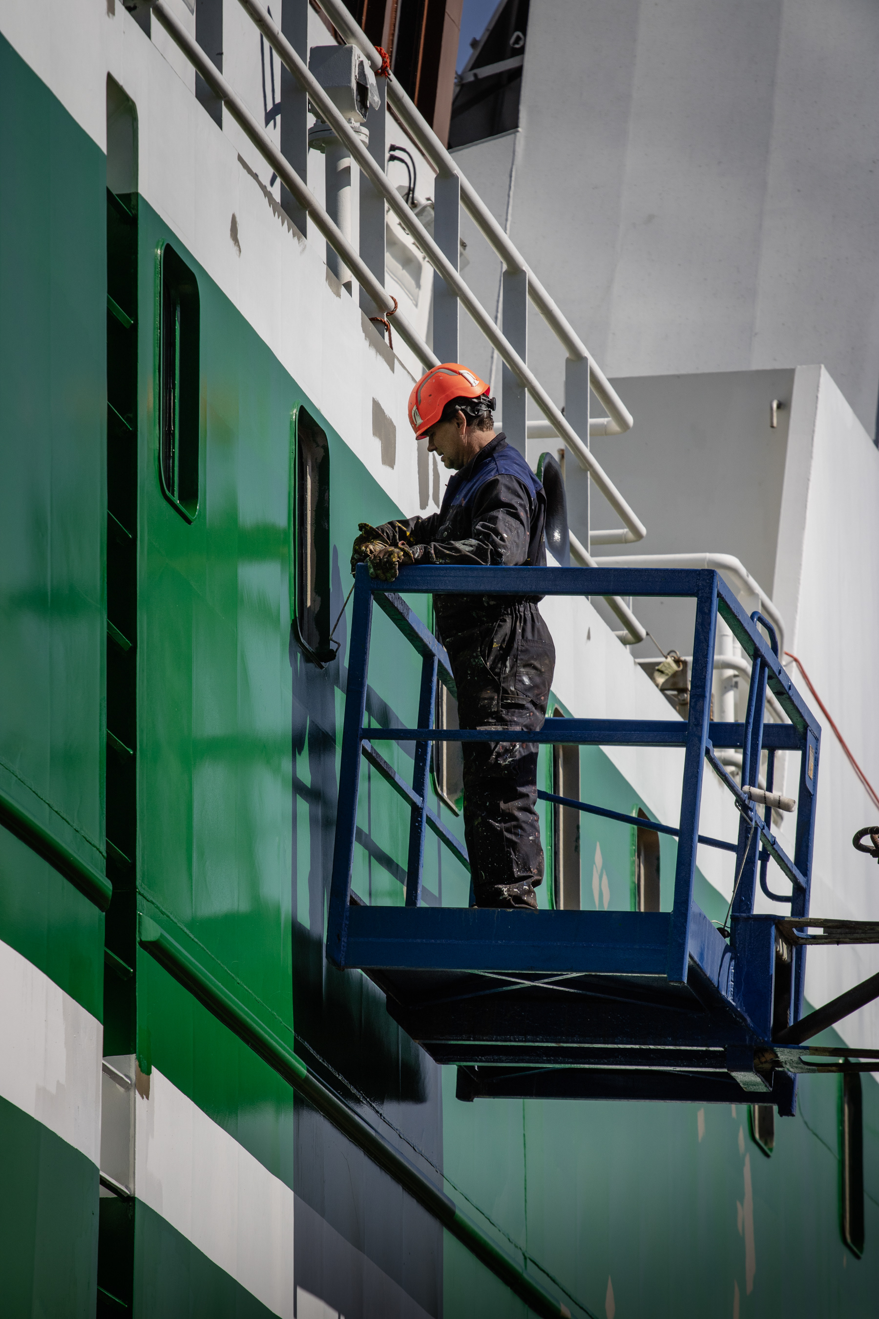 A maintenance man working on a green ship.