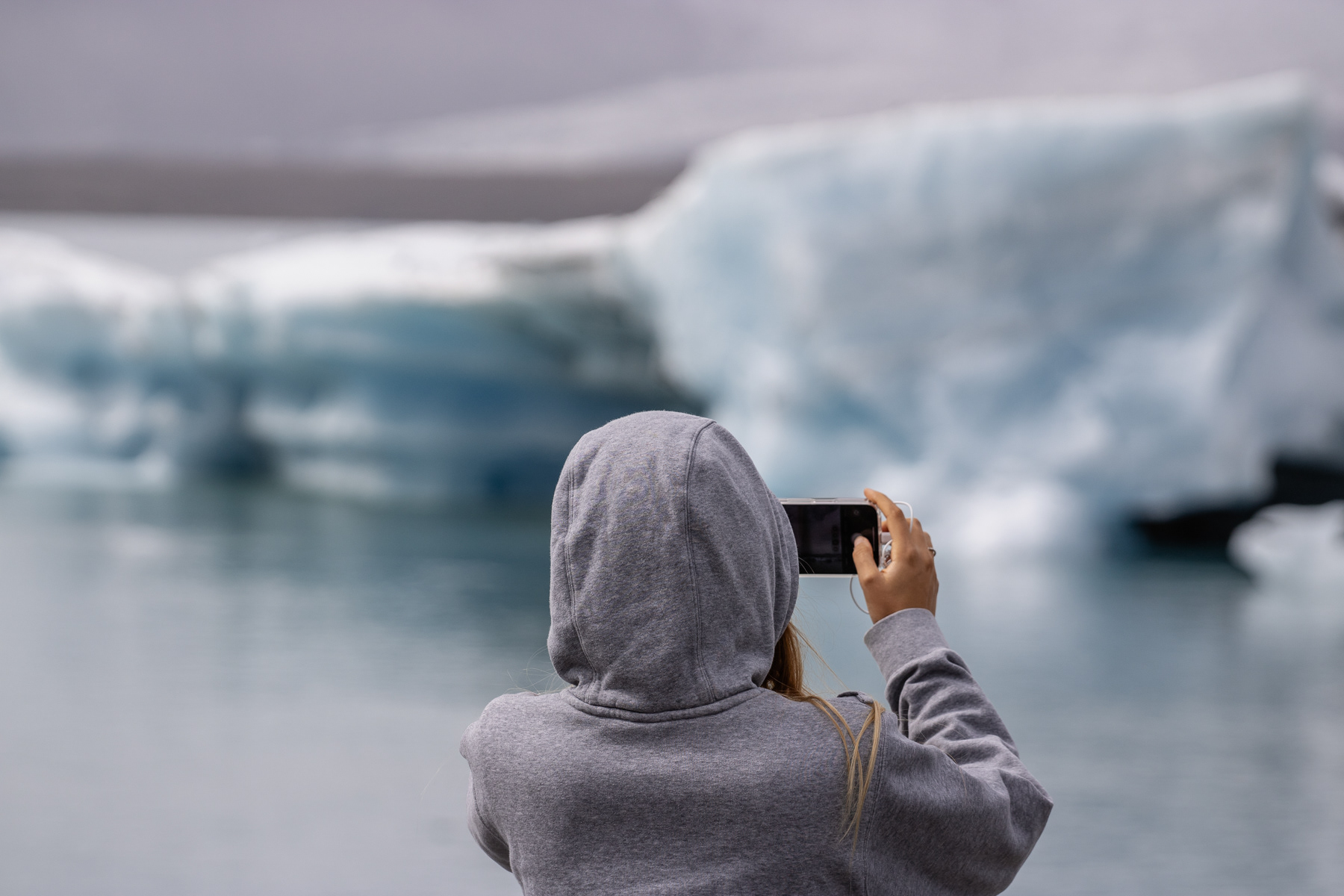 A woman taking a photo of the Vatnajökull glacier and Jökulsárlón glacier lake