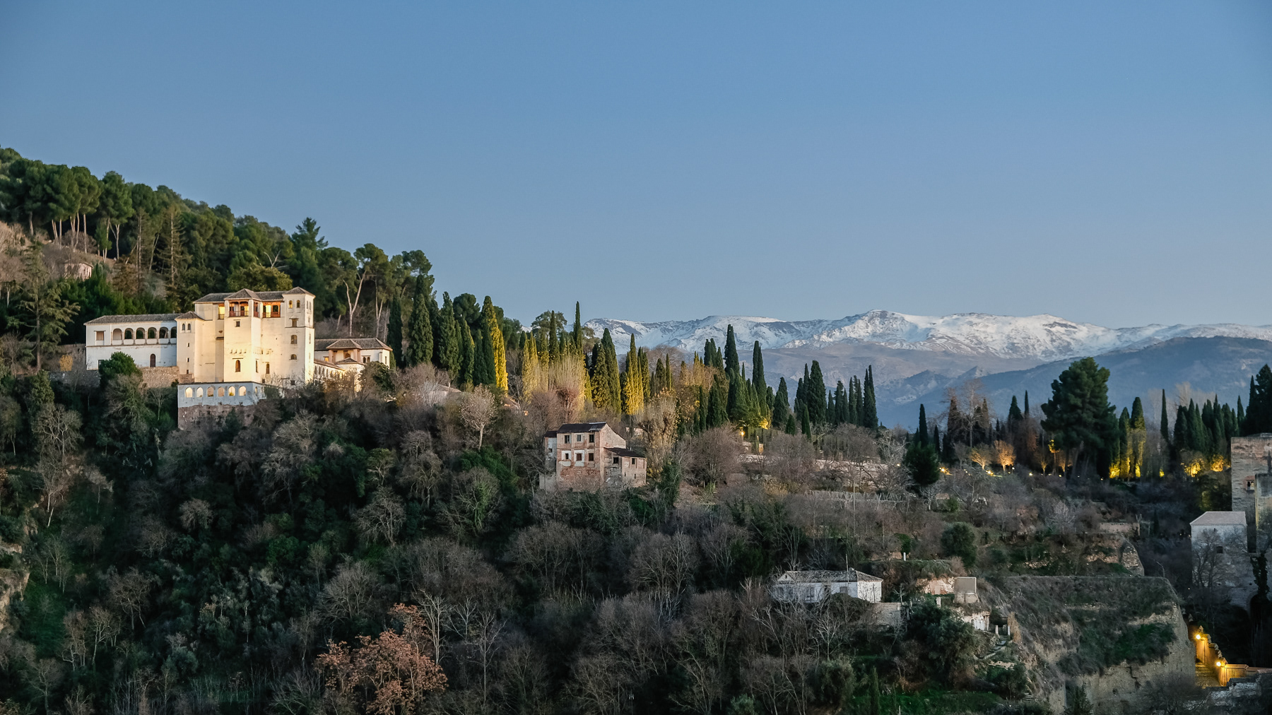 Evening falls, with the sun still lighting up the snowy peaks of the Sierra Nevada mountains.