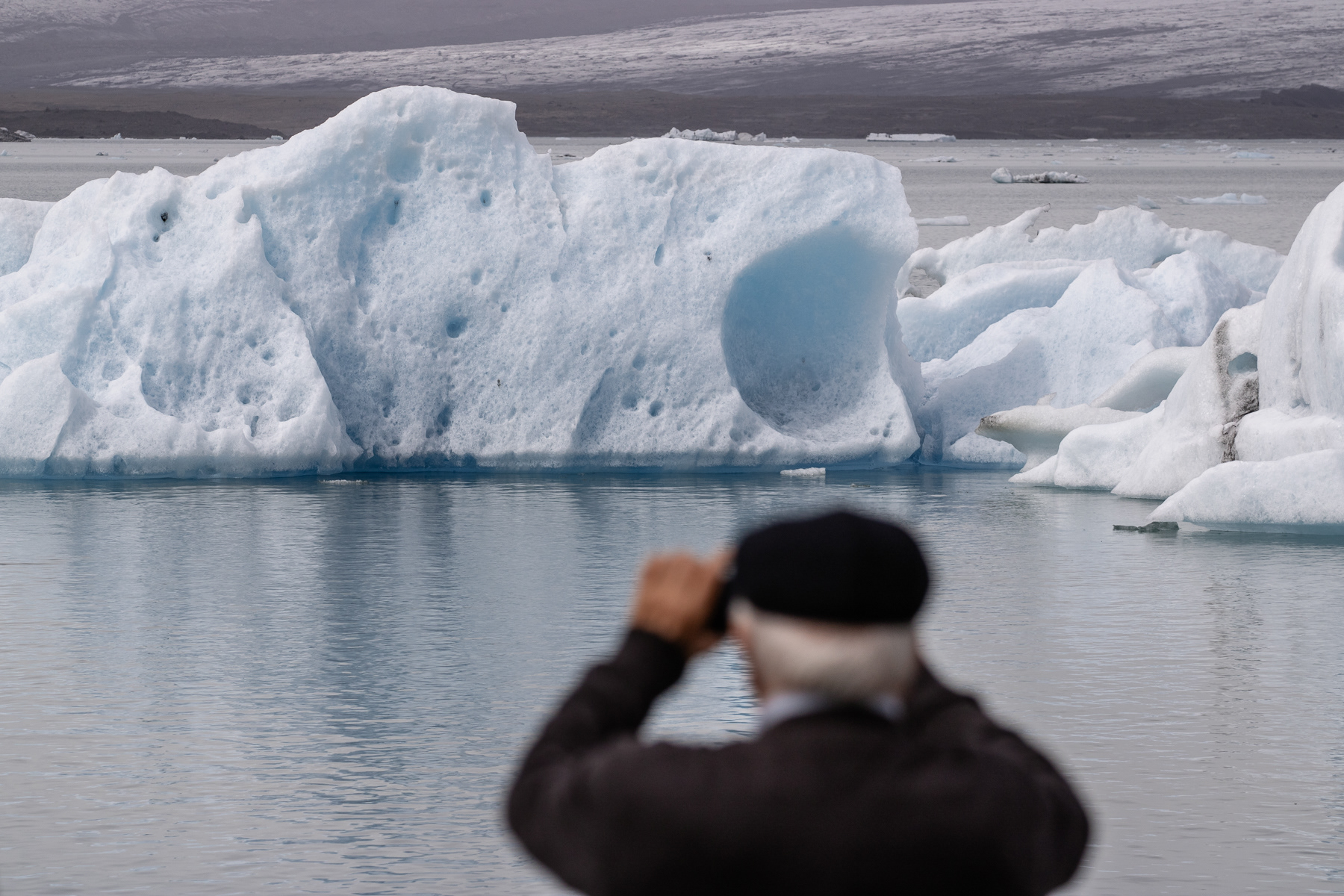 A man taking a photo of the Jökulsárlón glacier lake with the Vatnajökull glacier in the background, July 2025.