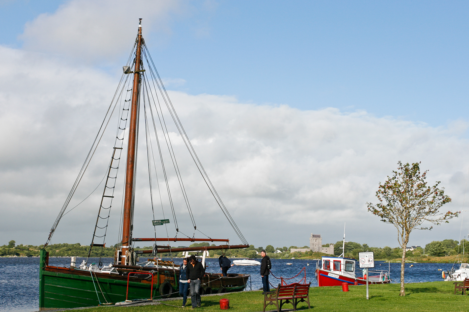 A sailing boat and a tiny fishing boat in the harbour of Kinvarra. In the background Dunguaire Castle