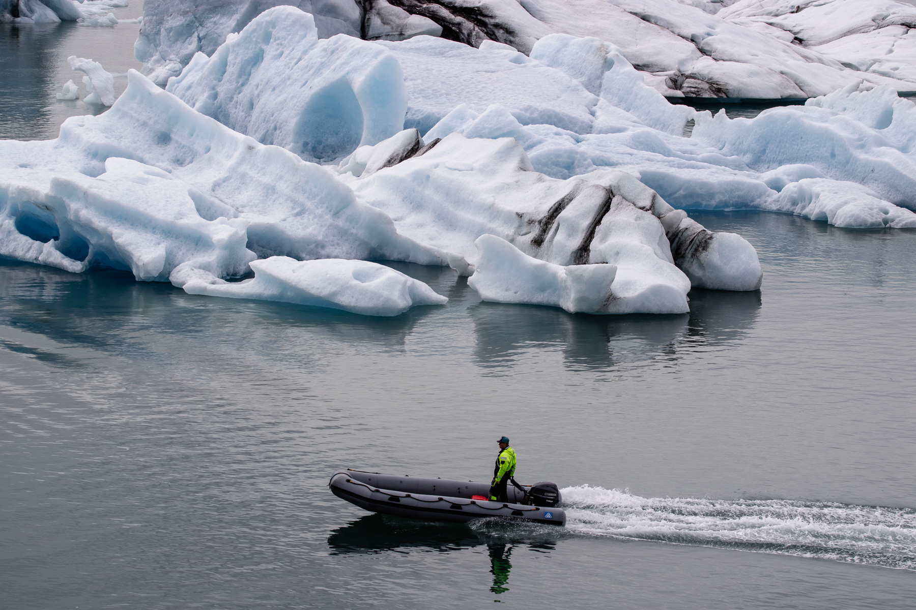 A rib with one safety employee cruising through the glacier lake.