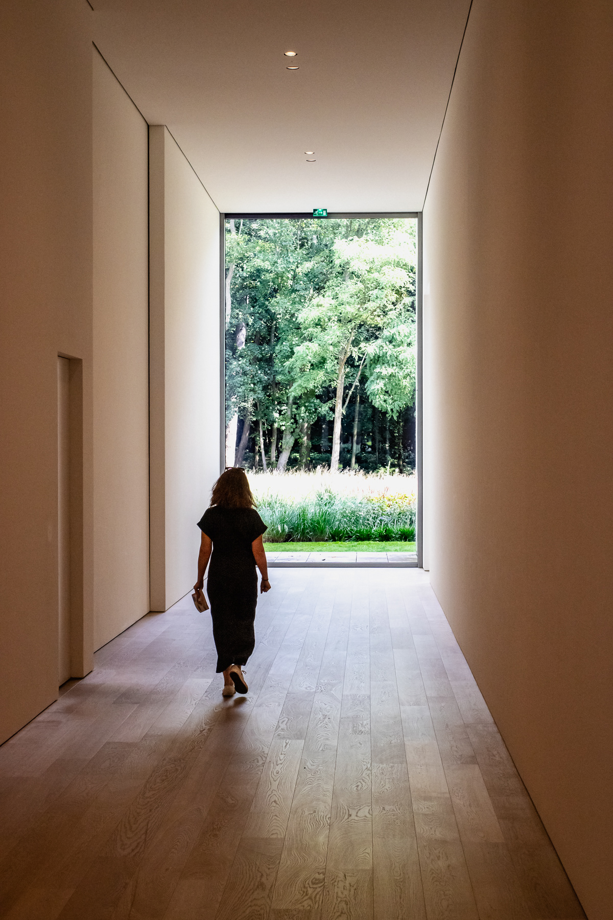 Hallway with wall-heigh windows with a view of the lushy garden.