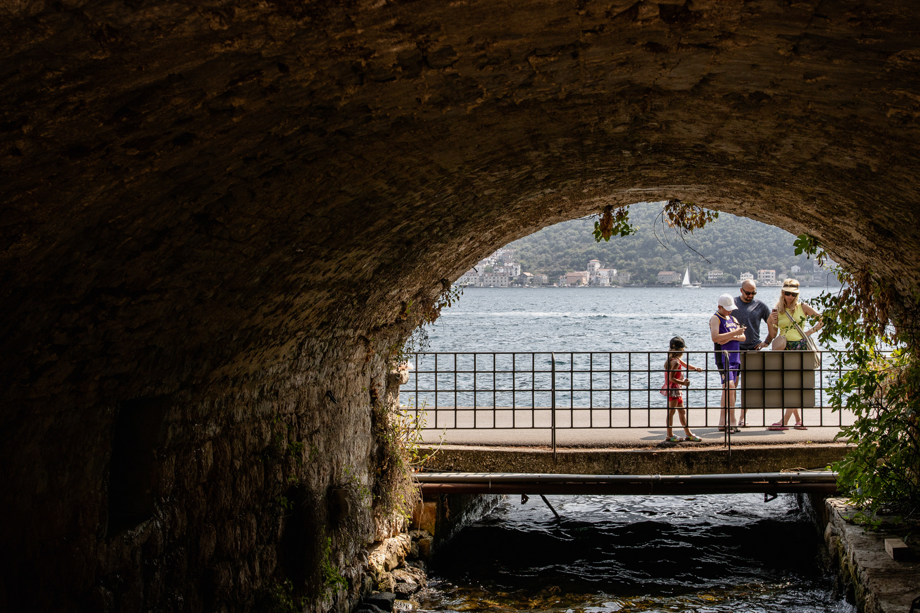 Family is reading a sign about the tunnel in Perast.