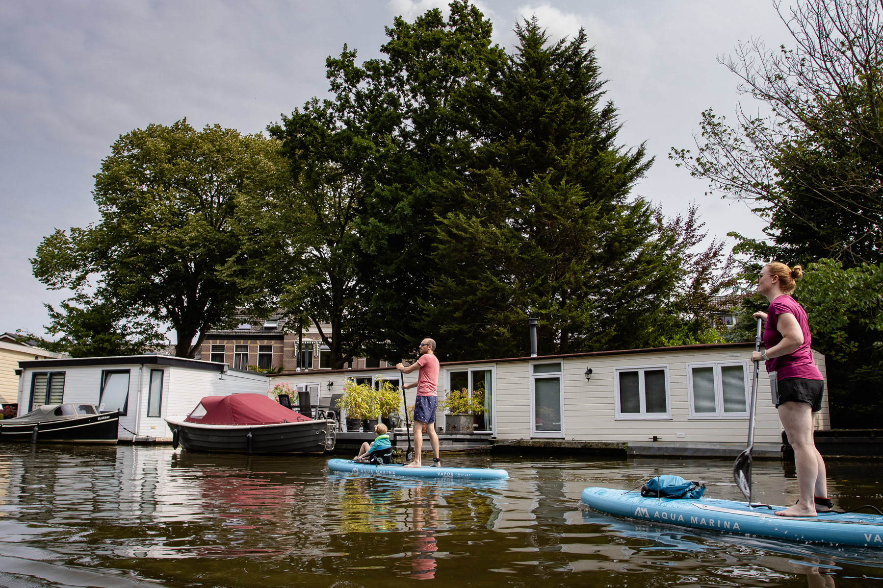 Two paddlers pass by a houseboast