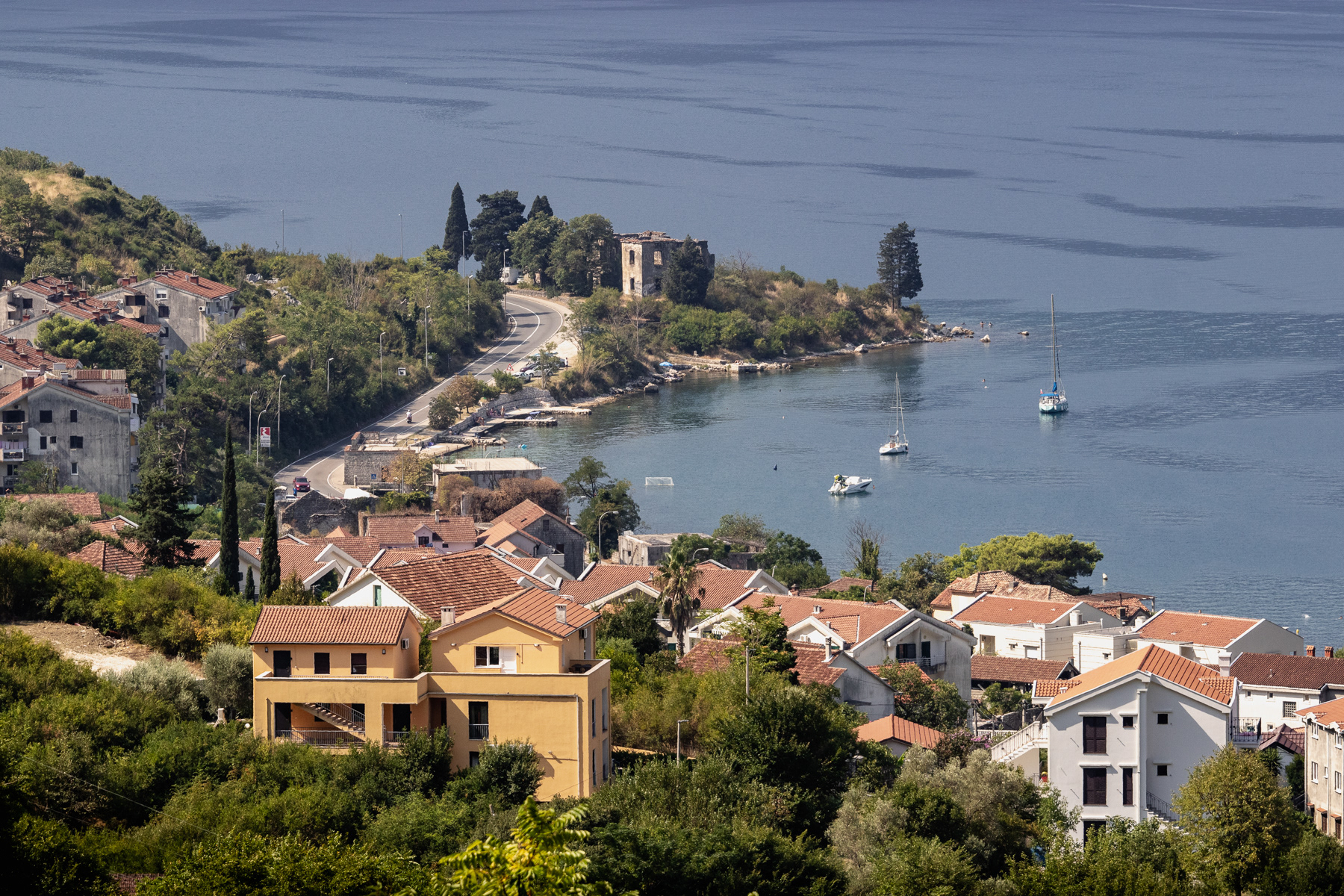 Long-lens shot of the bay near Risan, with a land point marked by a ruin.