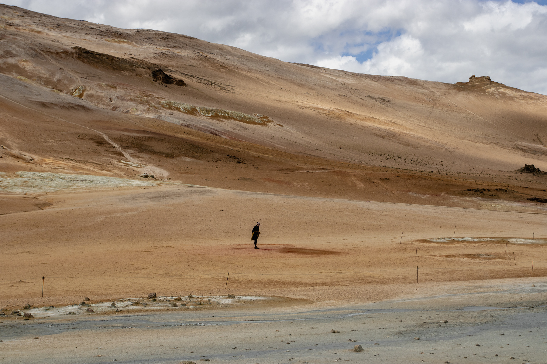 A rare moment, catching a single visitor against the backdrop of the lower hills at Hverir.