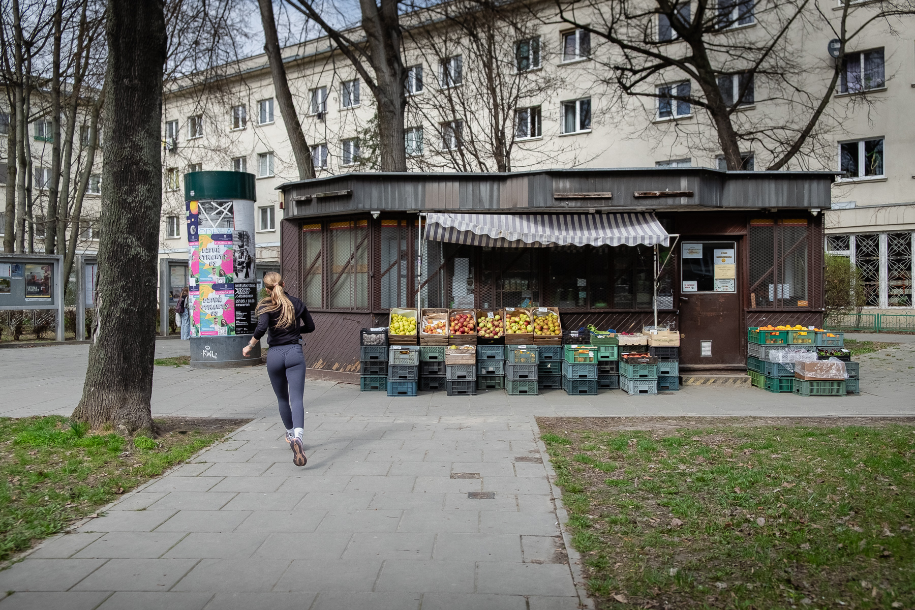A female runner passes the vegetables and fruit kiosk at Stefana Żeromskiego street.at 