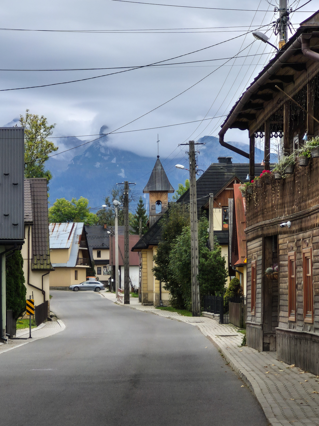 Jurgów's main street, with the Tatra Mountains partly covered in clouds in the background.