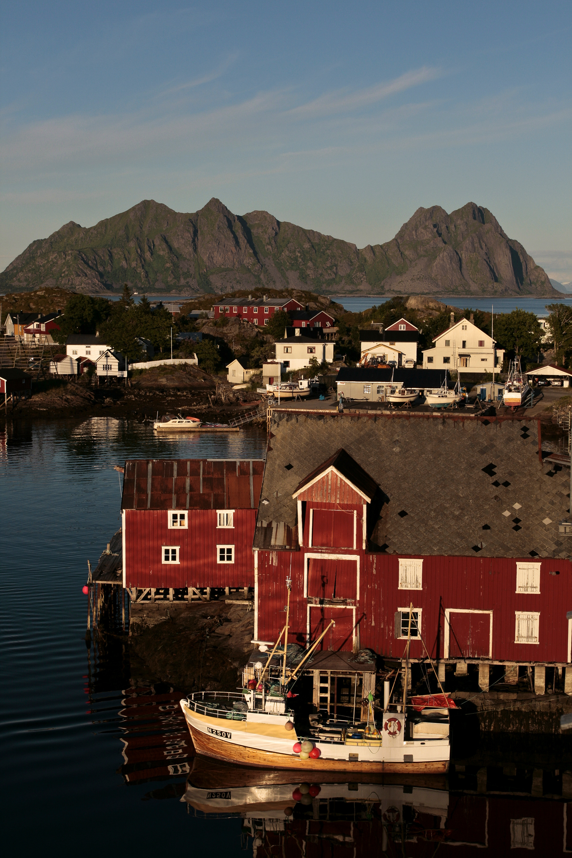 Historic working vessel N250V with historic warehouses in the harbour of Svolvaer