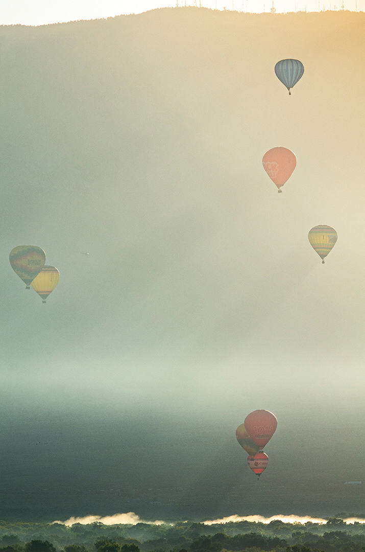 In the chill morning air, hot air ballons drift above the verdant green of the Rio Grande corridor and sun streamed shadows cut through the dust of morning.
