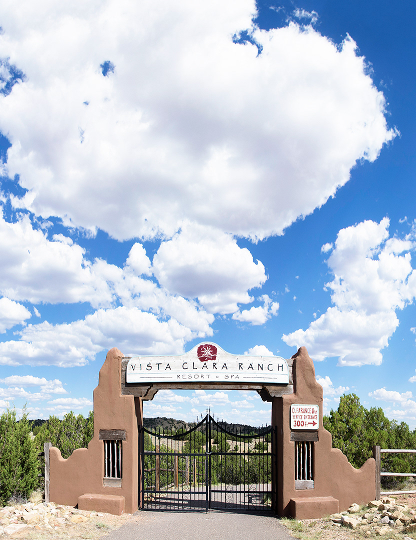 A deep blue sky filled with luminous afternoon clouds ignoring the adobe and wrought iron gateway for the previous Vista Clara Ranch