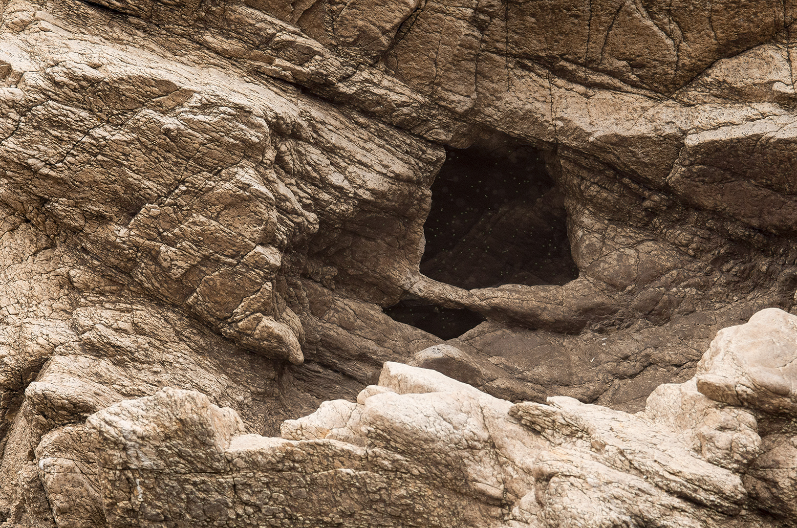 A natural rock entryway in a weather worn facade.  Who knows what's in it?