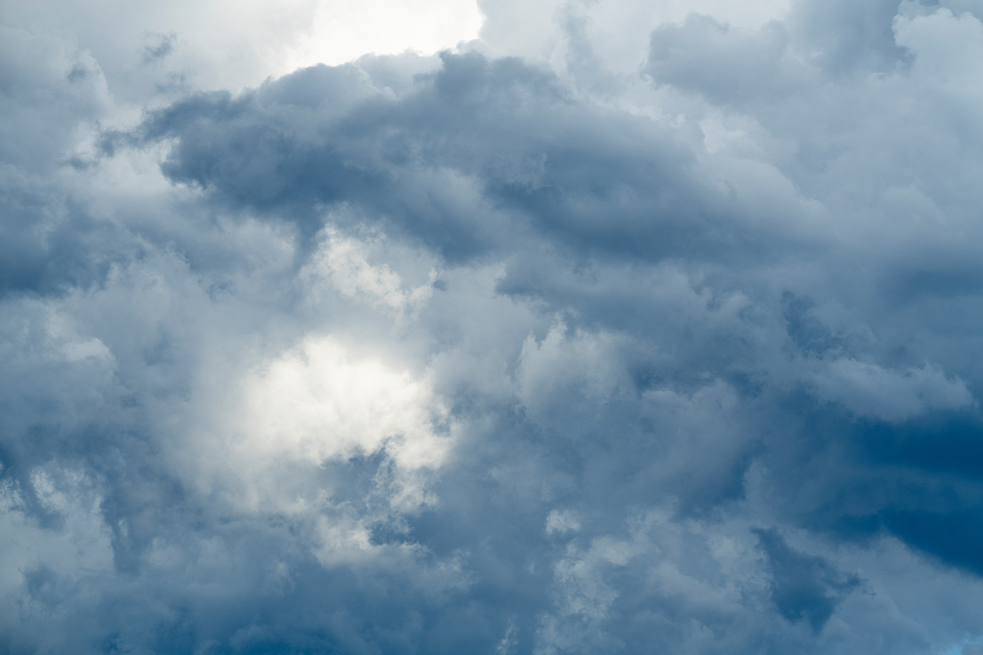 A deep shadowed grey blue texture of clouds encircles a gently illuminated detail