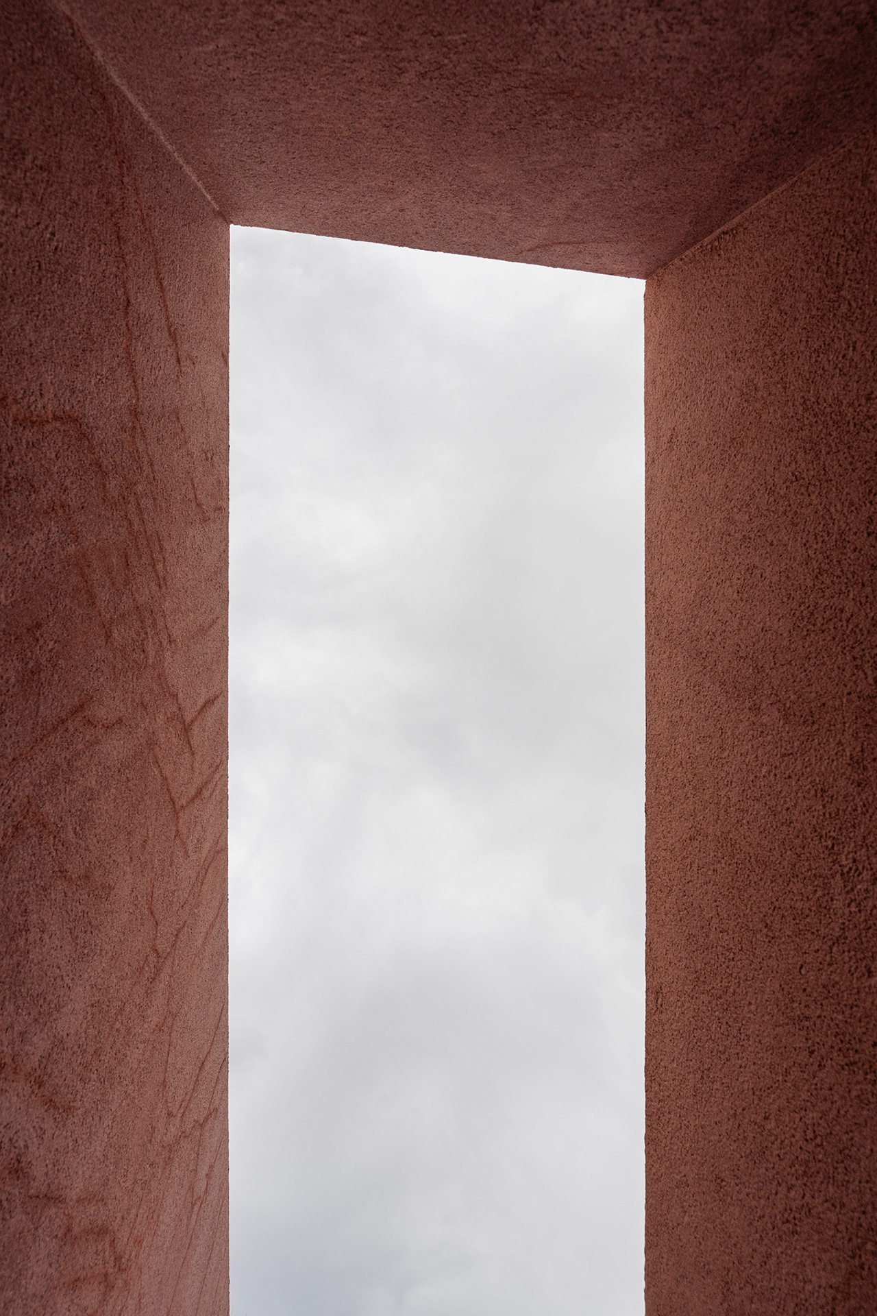 Looking through the crazed frame of red plaster walls up into a stormy grey sky