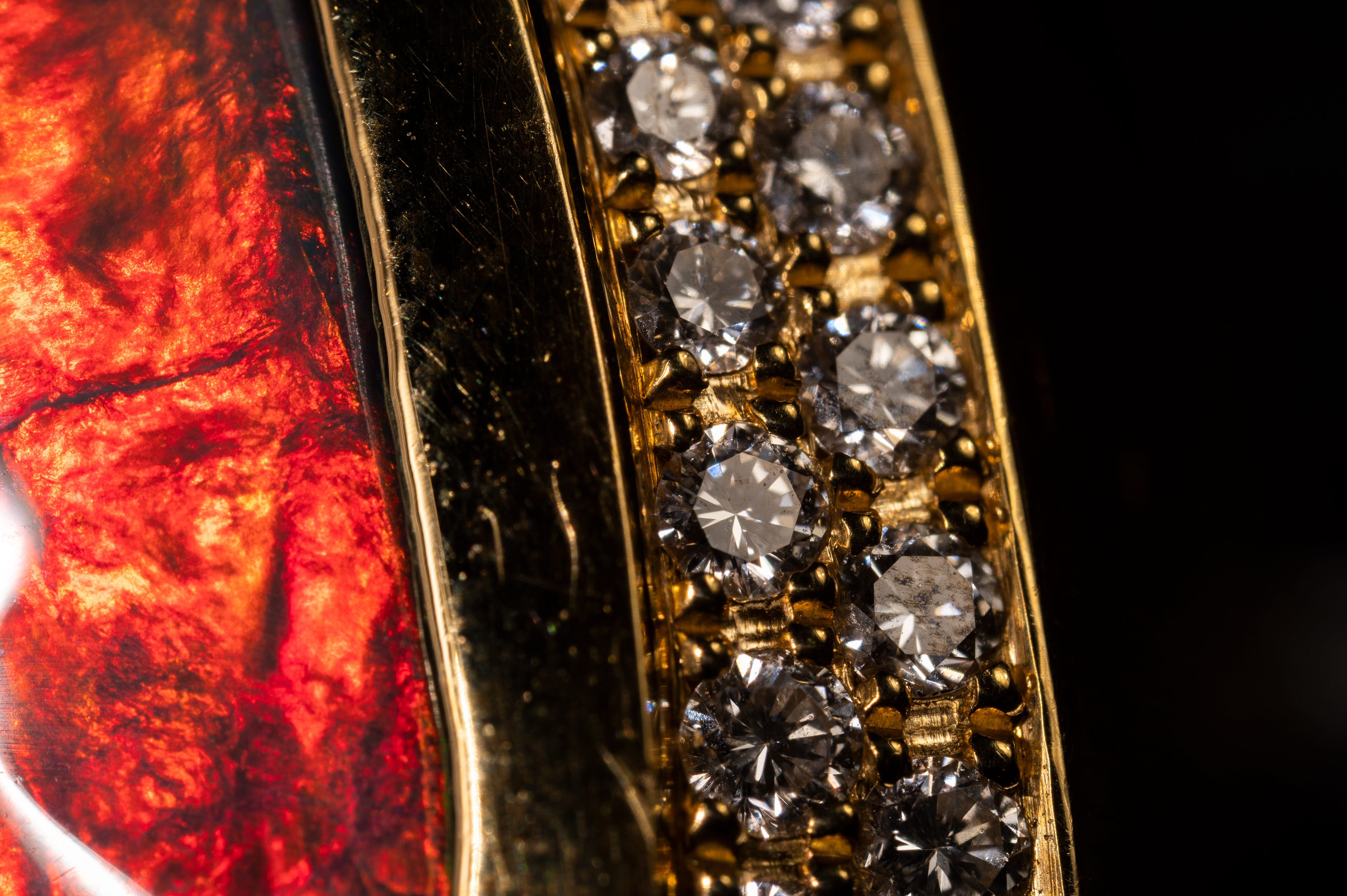 A detailed macro shot of an amazing black opal with brilliant red fire set in gold with a perimeter of diamonds by Ann Ziff - Tamsen Z