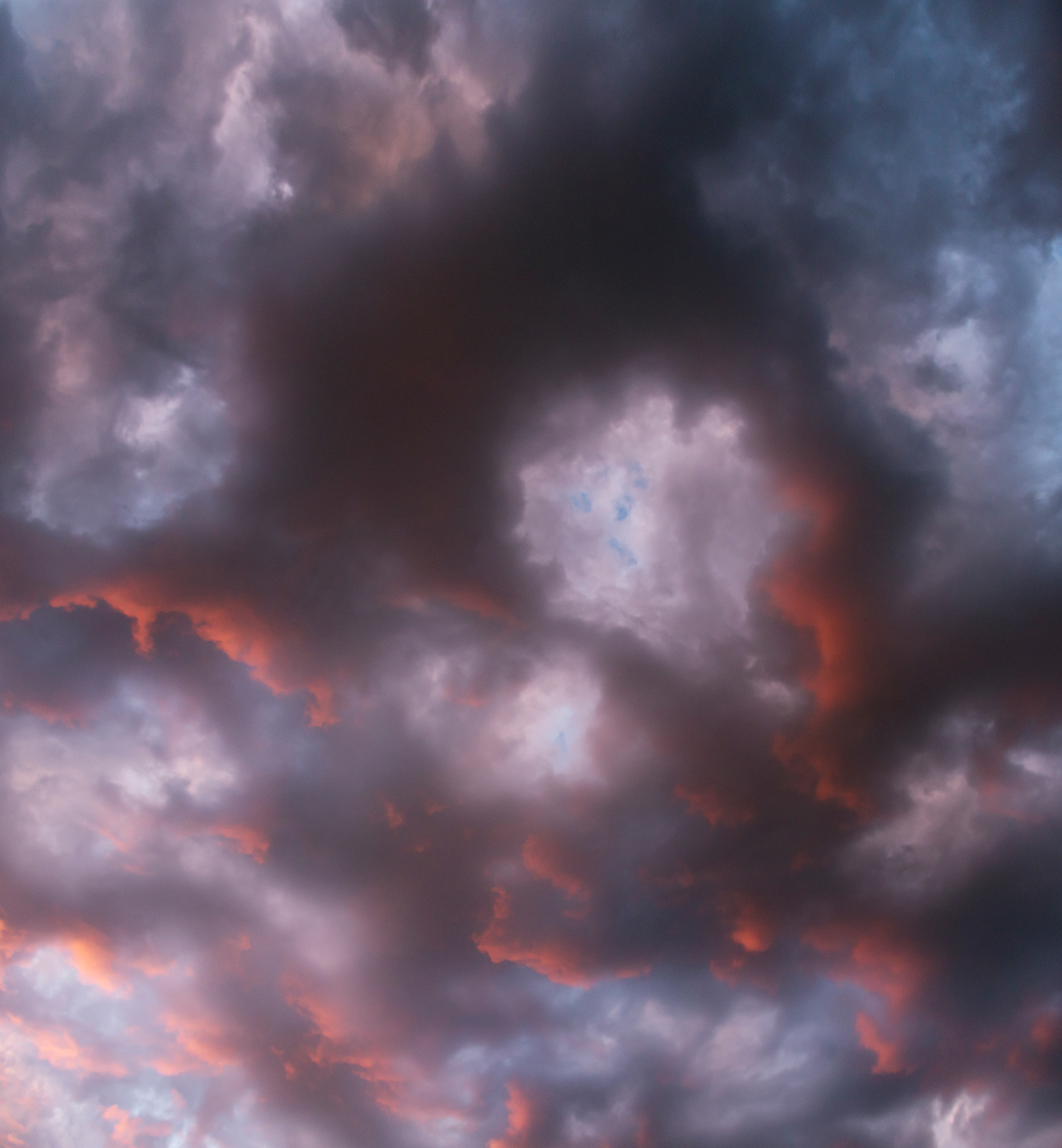 an intricate pattern of black clouds with bright burning edges of deep orange sunlight