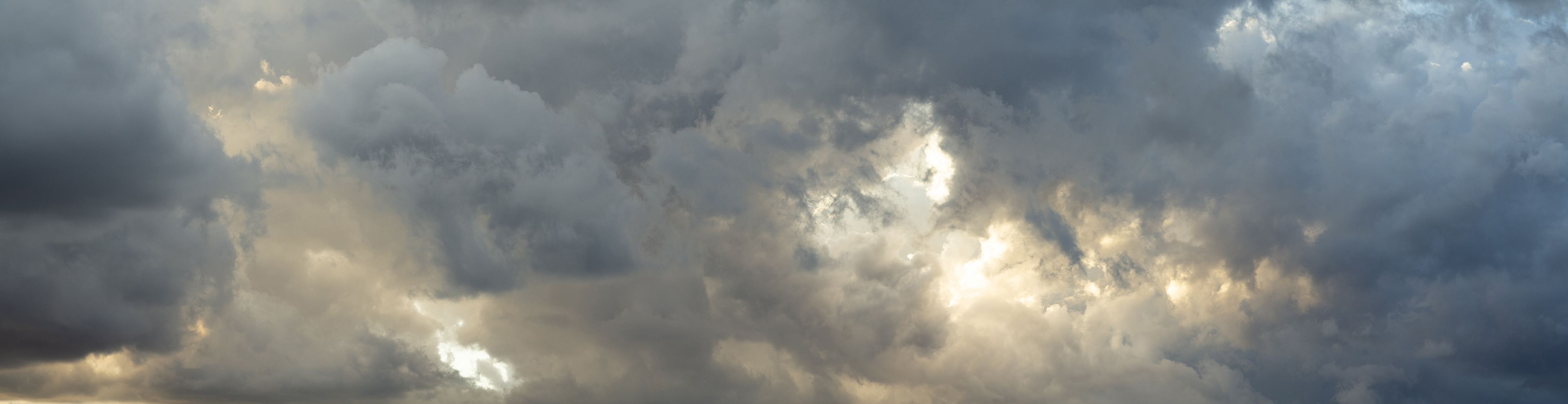 A dense bank of clouds filled with glowing sunset light and cloud blue shadows