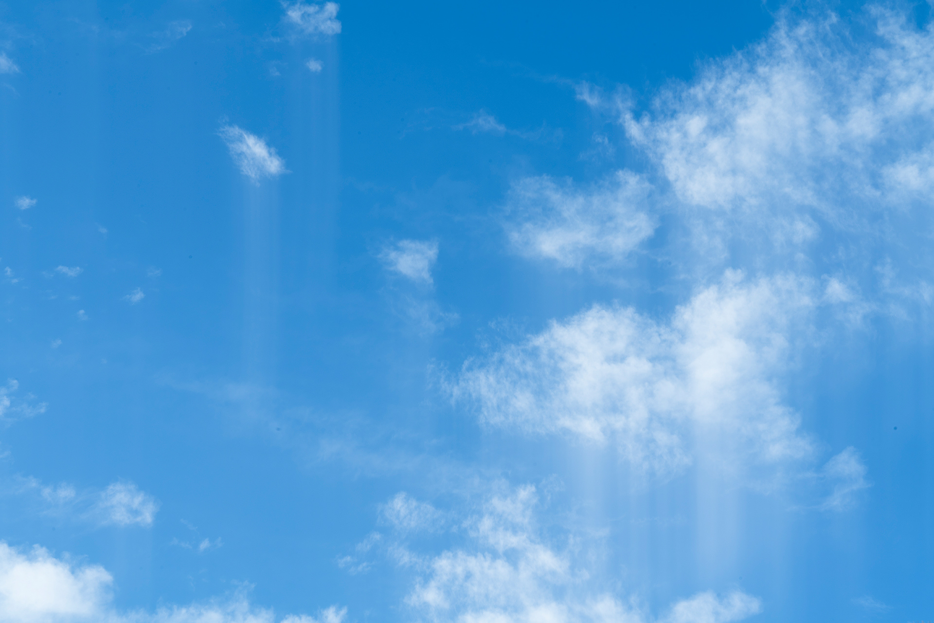 A bright blue sky speckled with small white clouds streaking downwards with intentional camera movement