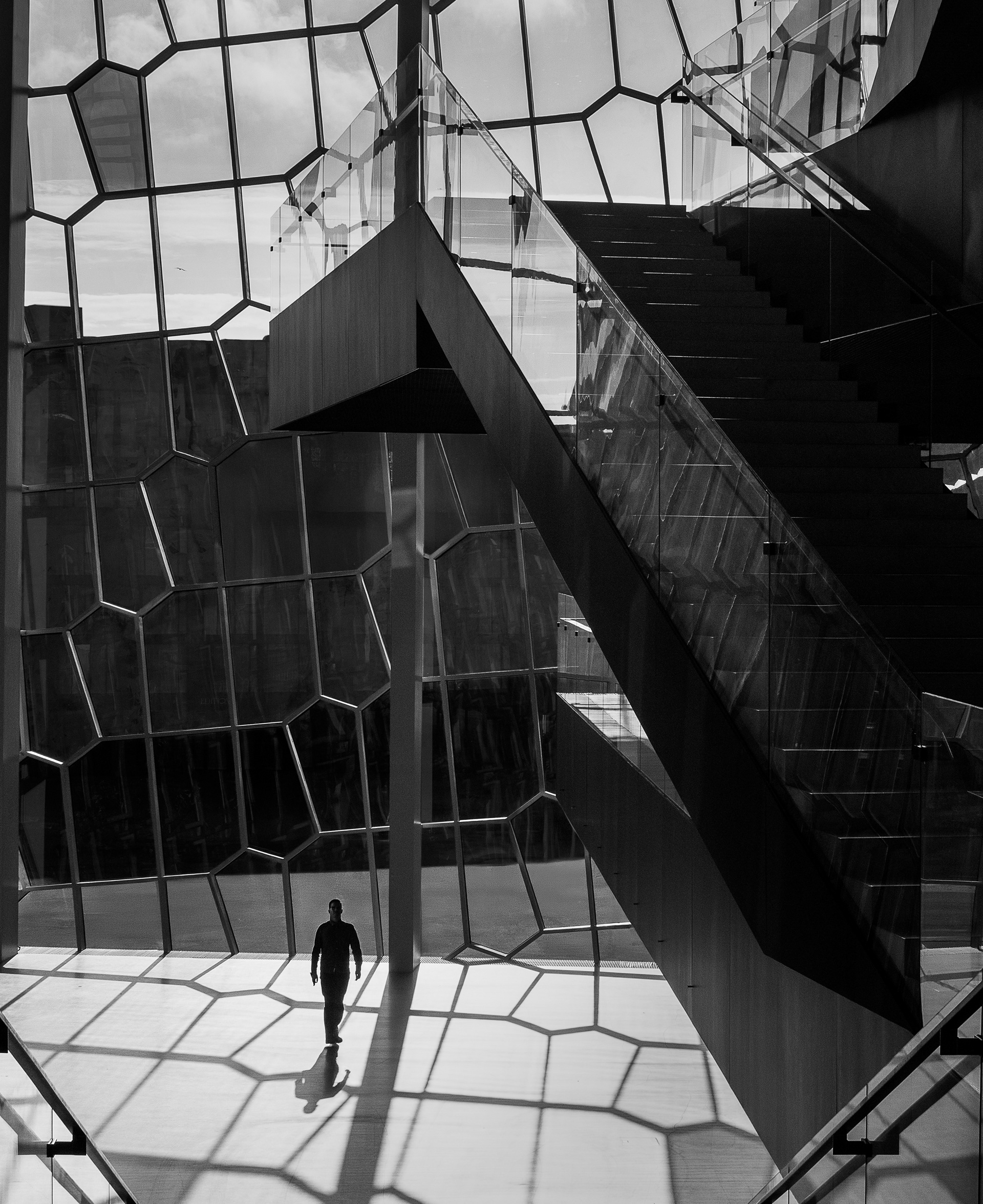 Black and white interior view of the staircase and geometric glass facade inside the Harpa Concert Hall in Reykjavík Iceland.