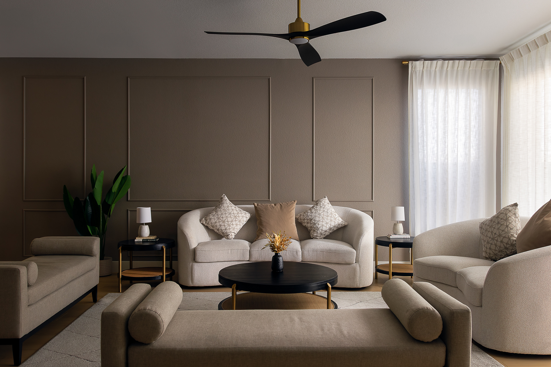Modern living room interior in a Las Vegas home featuring neutral furniture, curved sofas, a black round coffee table, and soft natural light.