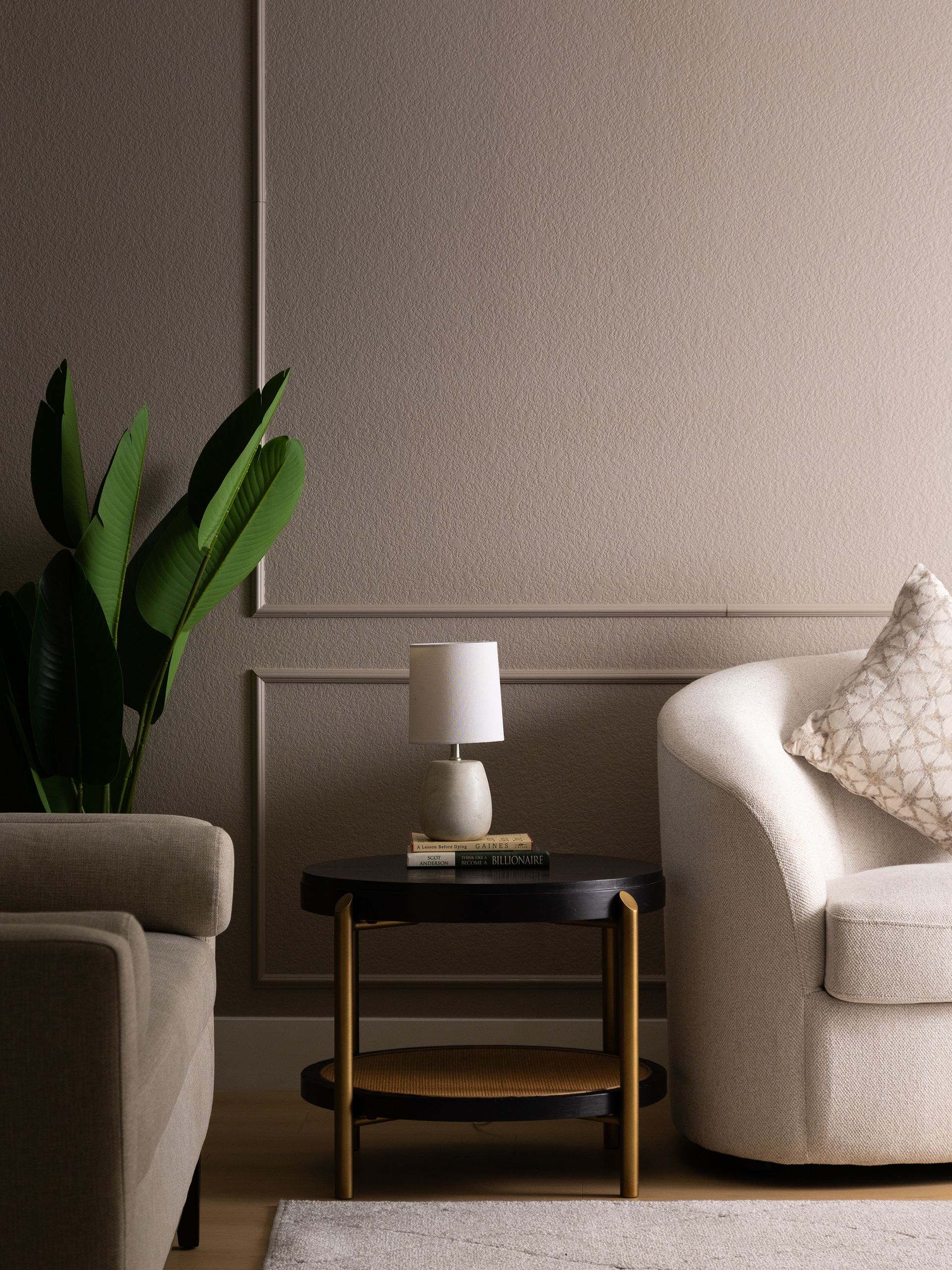 Neutral living room detail in a Las Vegas home featuring a black round side table with lamp, upholstered seating, and decorative wall paneling.