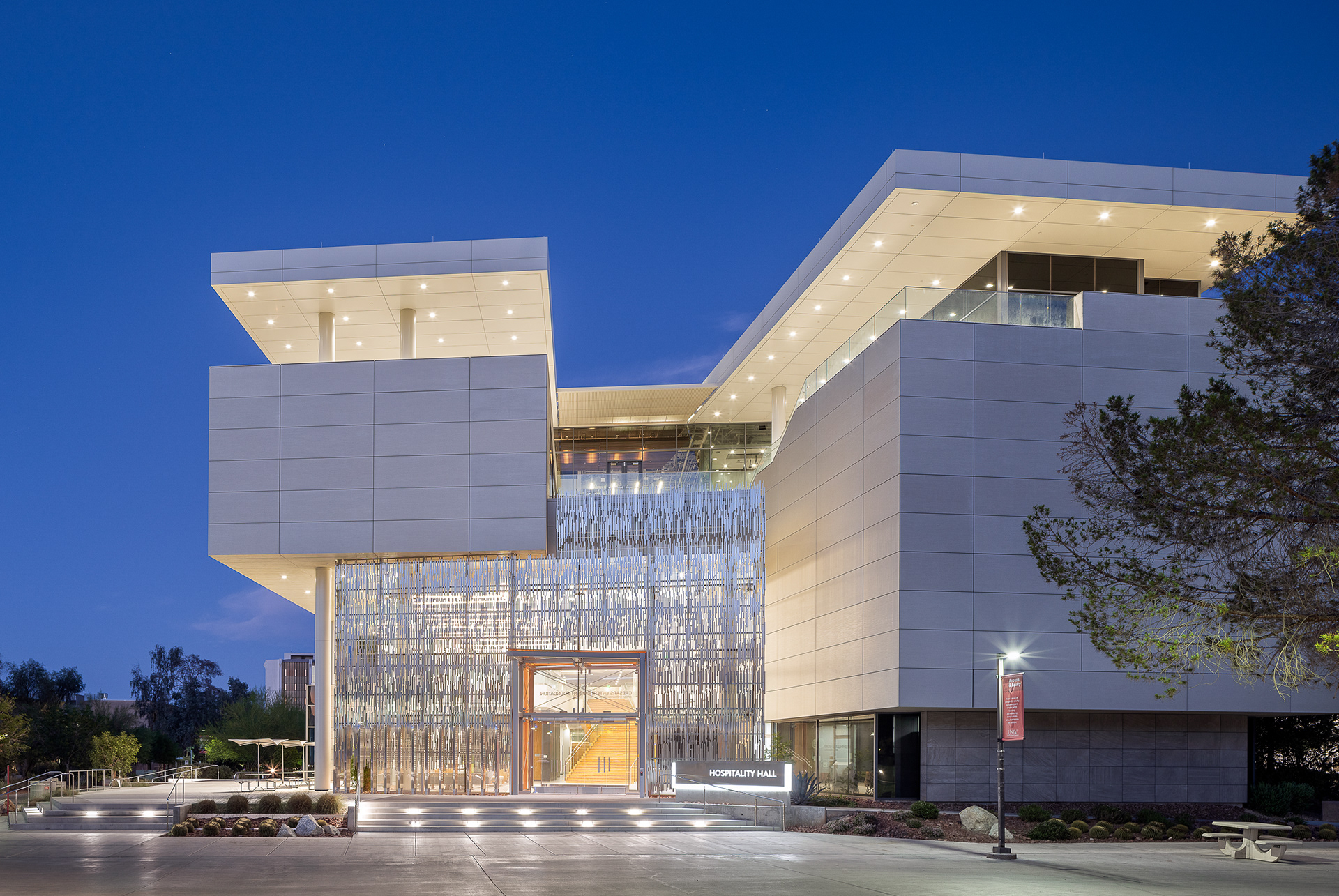 UNLV Hospitality Hall exterior at twilight in Las Vegas with modern glass entrance and illuminated architectural facade