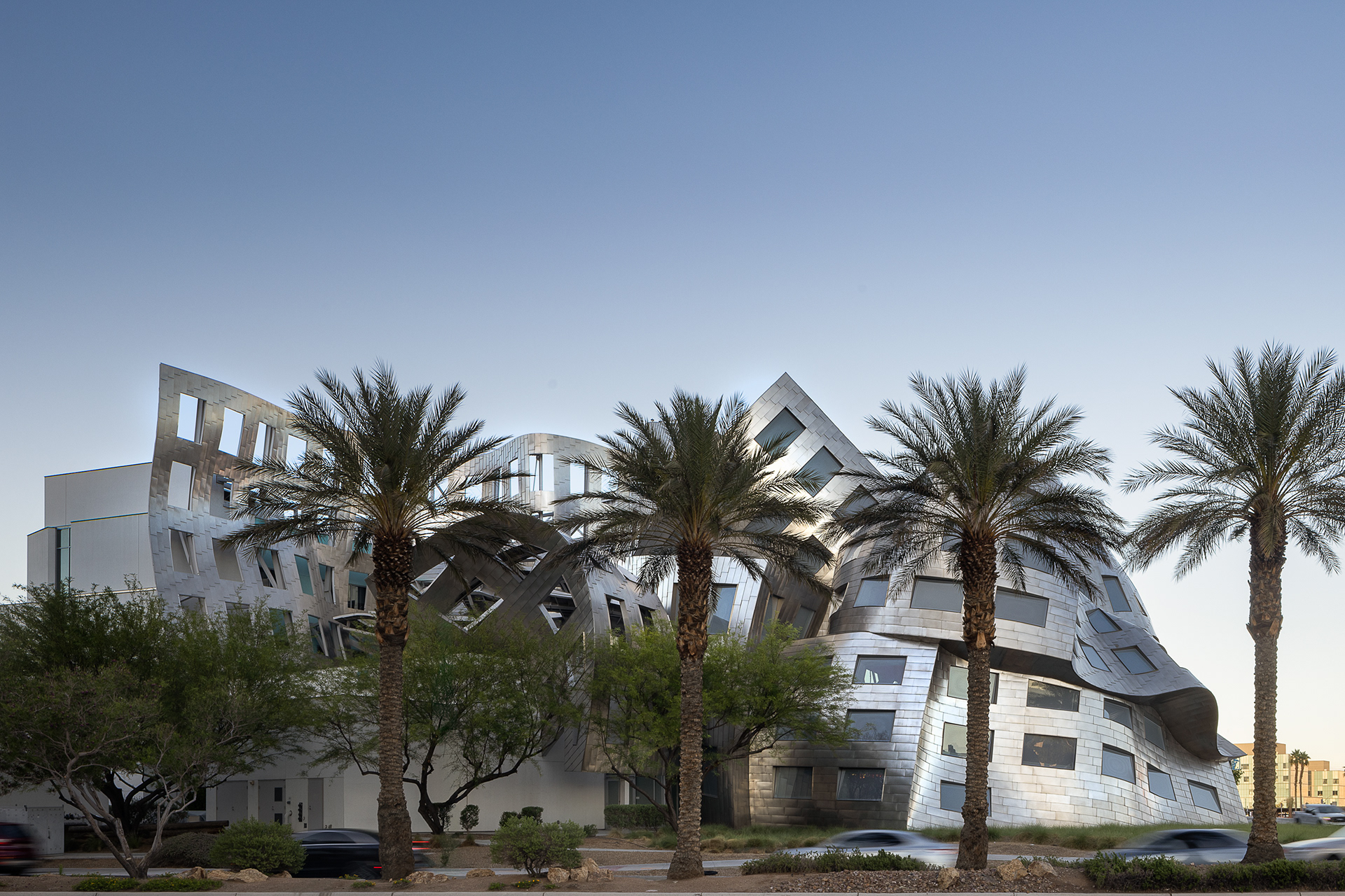 Exterior of the Cleveland Clinic Lou Ruvo Center for Brain Health in Las Vegas Nevada featuring the sculptural stainless steel facade and palm trees in the foreground.