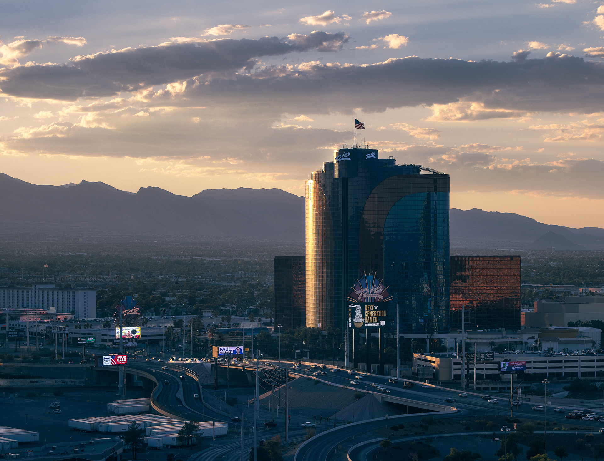 Rio All Suite Hotel and Casino tower at sunset in Las Vegas with highway interchange and mountains in background