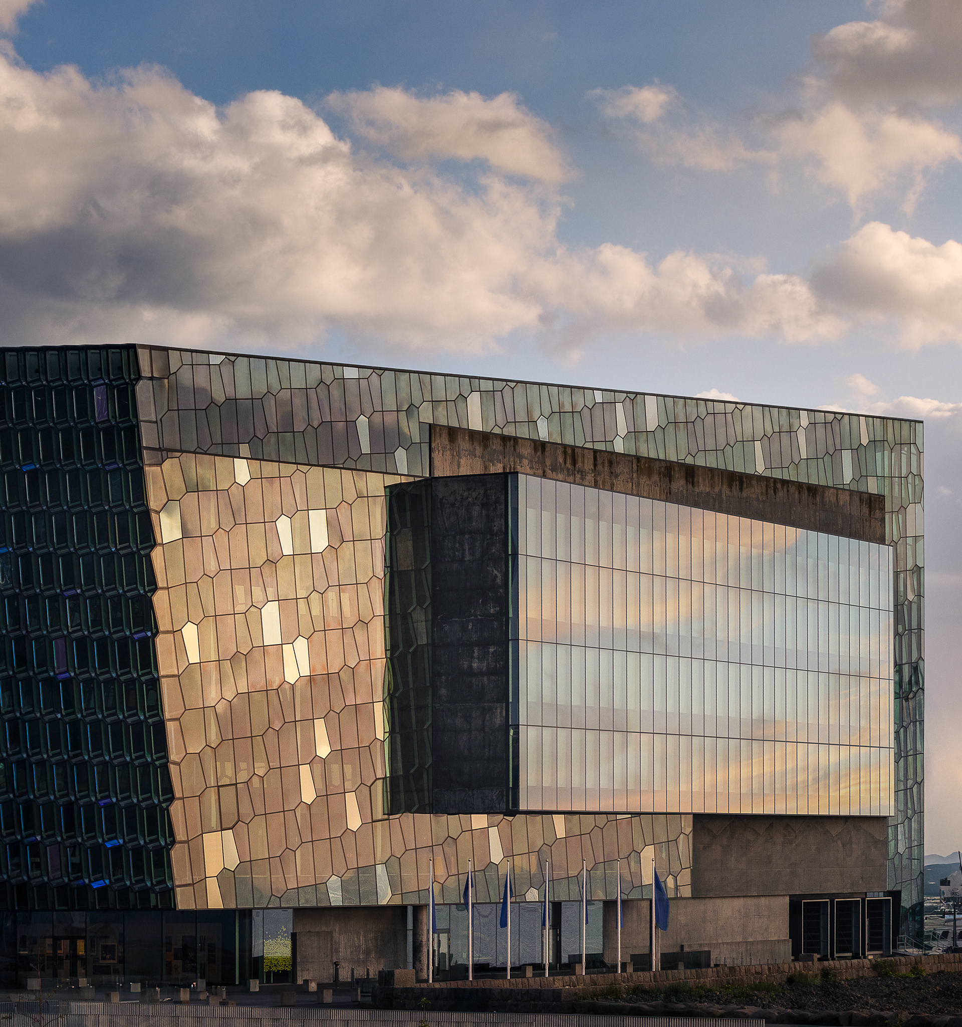 Exterior view of Harpa Concert Hall in Reykjavík Iceland with geometric glass facade reflecting warm evening light.