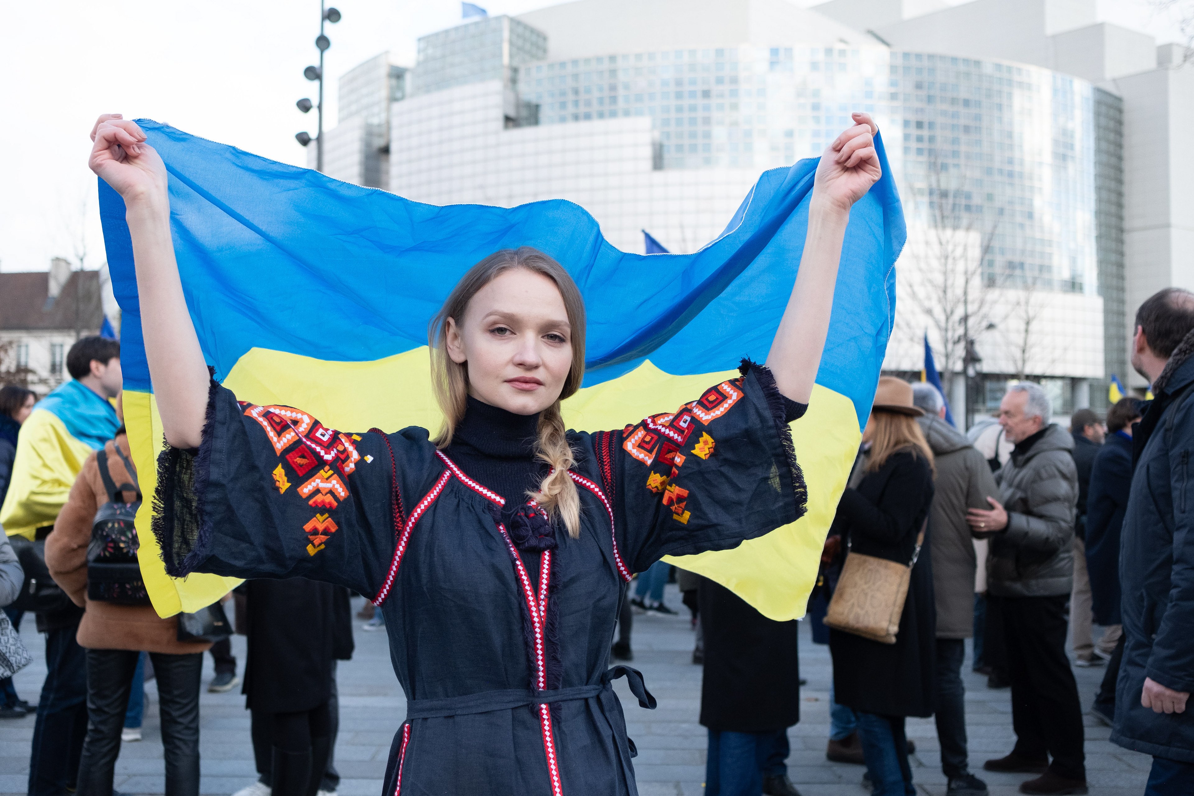 Une manifestante déploie derrière elle le drapeau ukrainien.