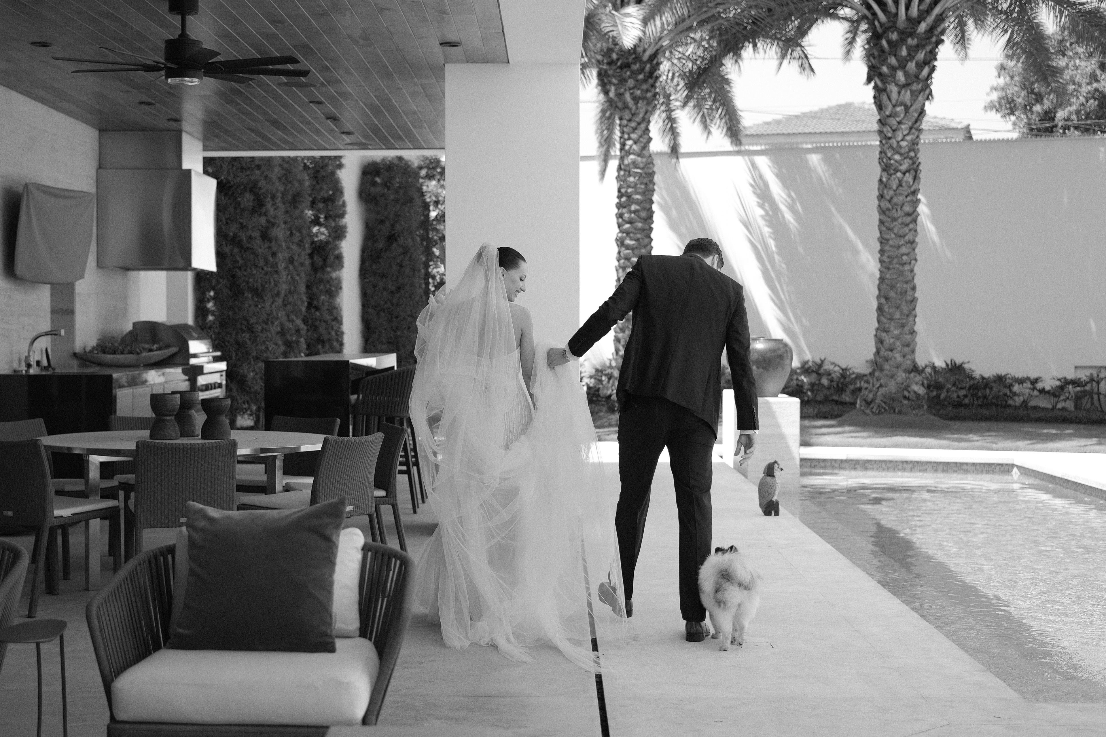 Bride and groom walking hand in hand by the pool with their dog in San Pedro Garza García — timeless wedding moment captured by Velora Weddings