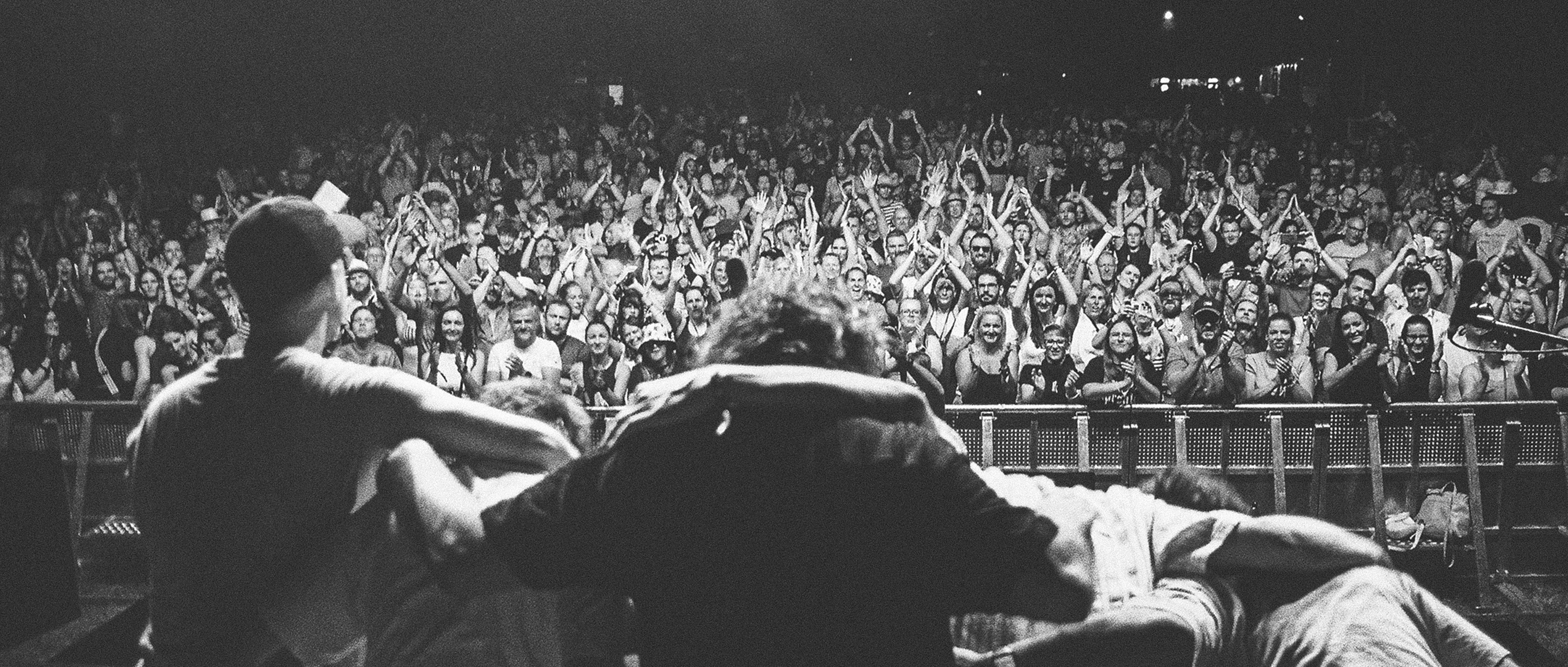 Wide analog shot from behind the band Billy Barman looking at a massive cheering crowd at Zakovic Open festival / Širokouhlý analógový záber zo zákulisia na kapelu Billy Barman a tlieskajúci dav na festivale Žákovic Open.