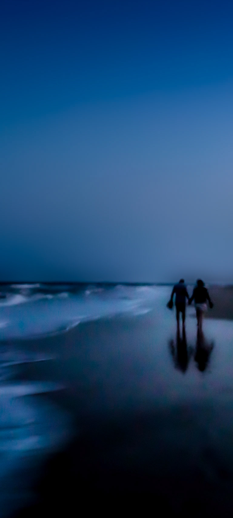 A couple at a romantic beach walk in the late evening.
