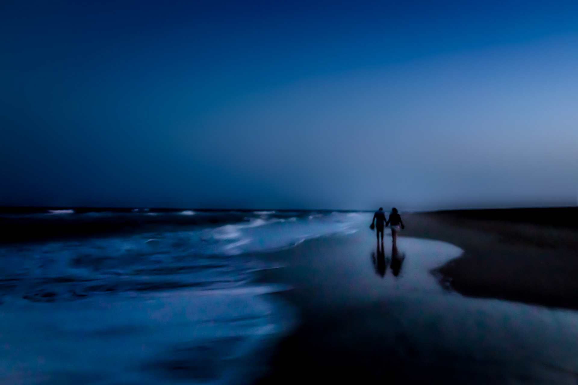 A couple at a romantic beach walk in the late evening.