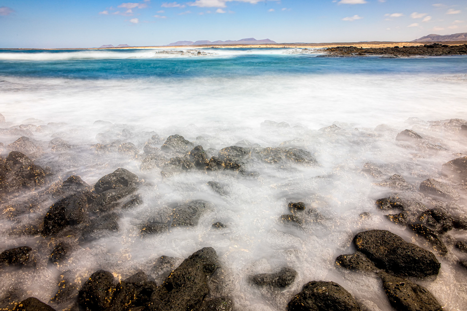 Waves are rolling in at the coast near Faro El Toston
