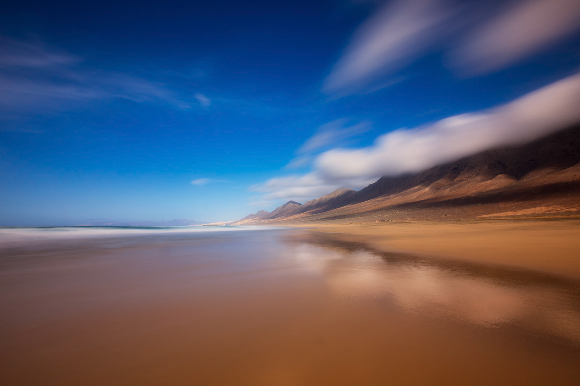 The mountains are reflecting in the wet sand of Playa Cofete
