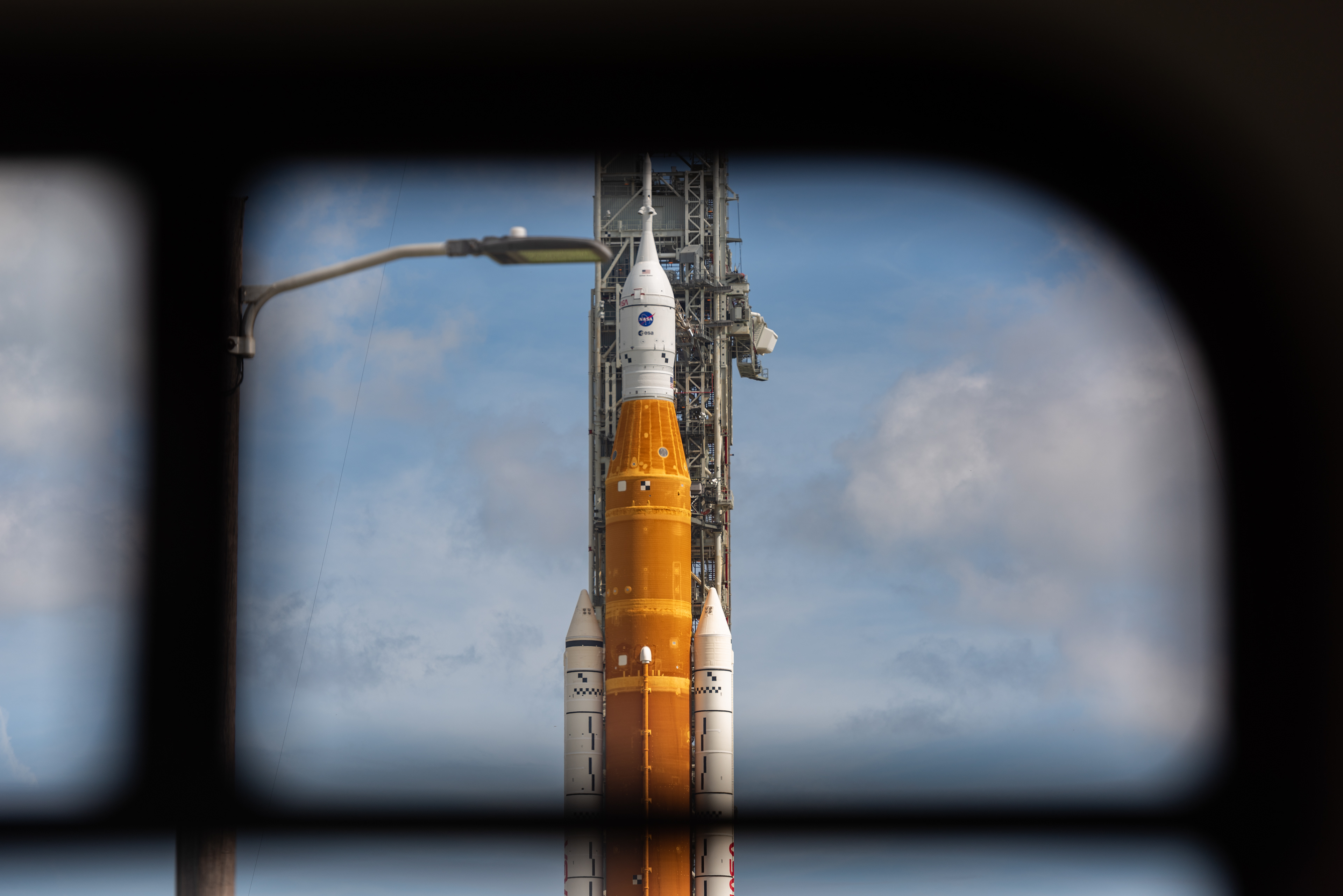 NASA's SLS rocket is seen through the window of a bus transporting members of the media. August 2022.