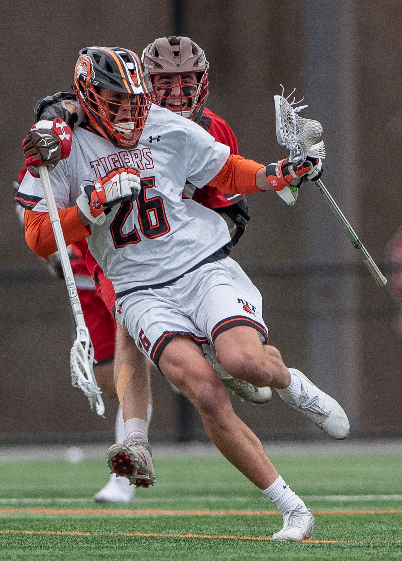 Sophomore midfielder, Andrew Powlin of RIT(26), takes a wraparound check from Junior attackman Conor Caffrey(14) of St Lawrence during the RIT St Lawrence at the RIT Turf in Henrietta NY, on April 20th, 2019. RIT won 11-7
