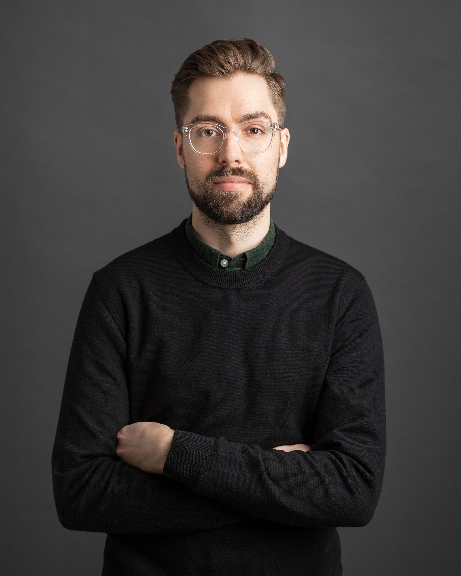 Studio portrait of Eliot Wright wearing clear glasses with a dark sweater