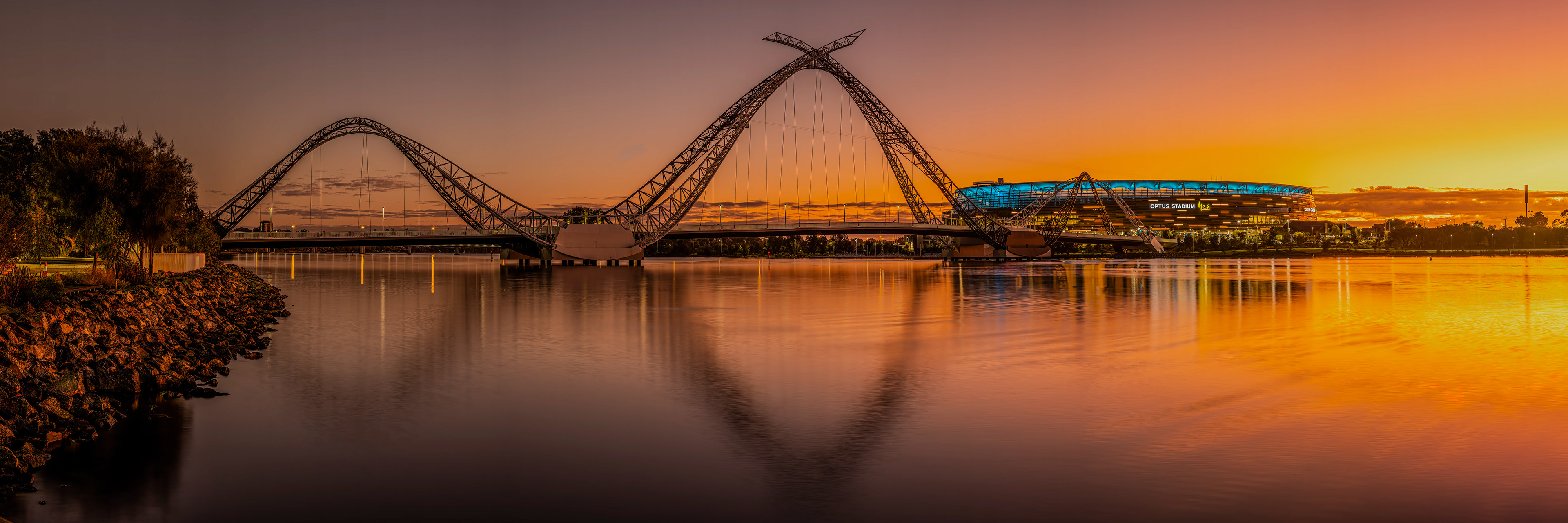 Sunrise panorama on the Swan River at East Perth with the pedestrian Matagarup Bridge and Optus Stadium receiving the morning sun.