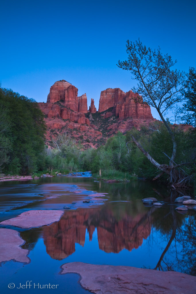 A dramatic rock formation reflected in a creek at dusk