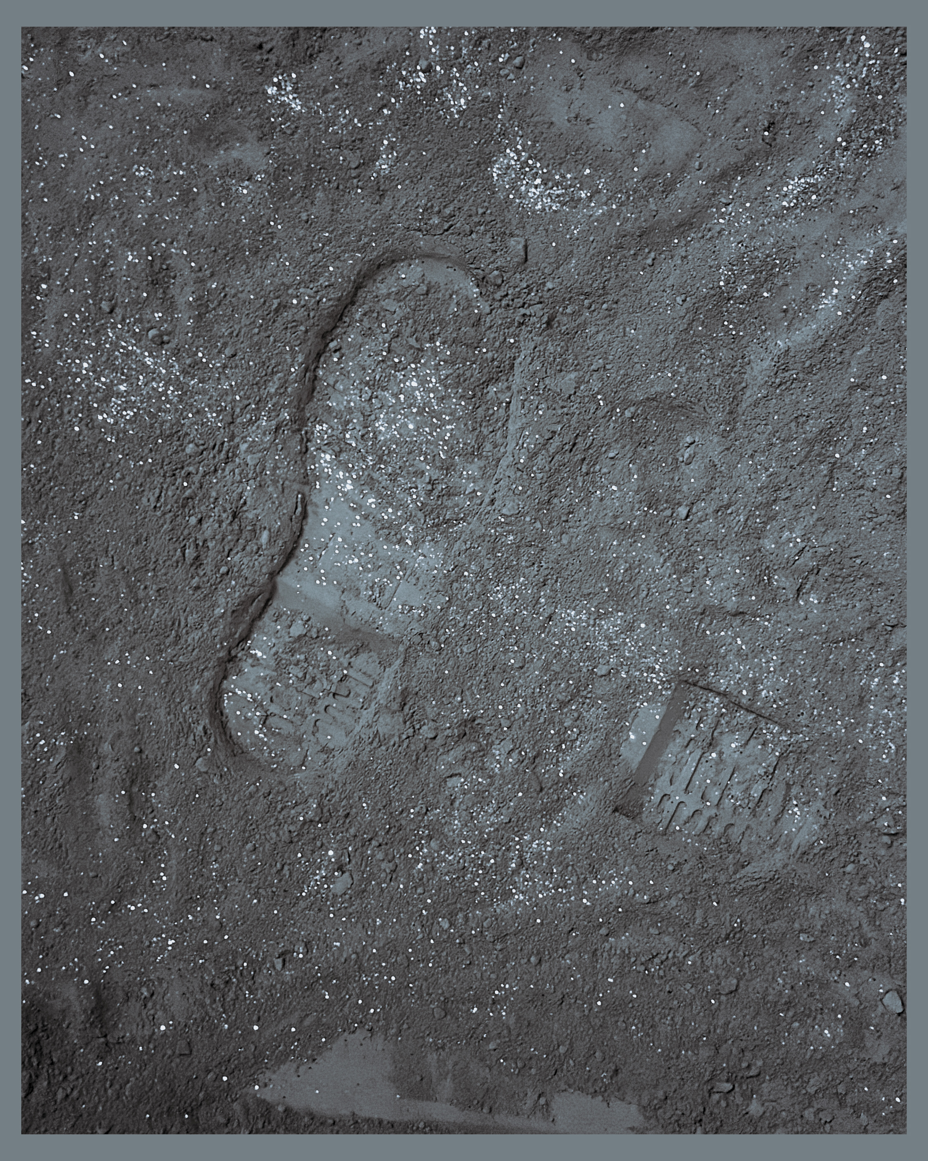 Photo: A close-up of a bootprint in fine, dark gray dust with shimmery particles.