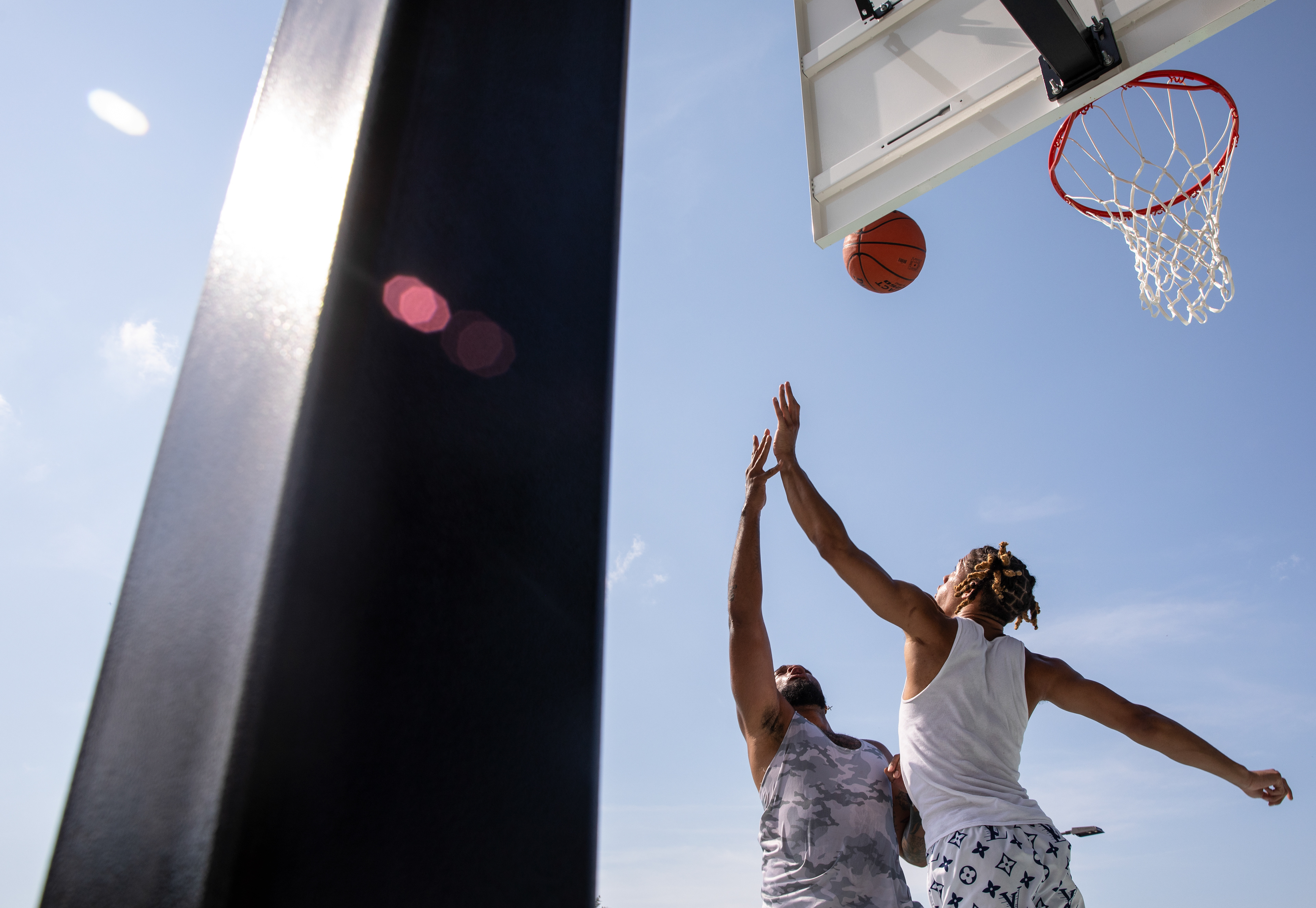 St. Louis resident Marquis Wright, left, goes up for a layup past Chris Spaete of St. Louis during a pickup game on the opening day of the new basketball courts in St. Louis' Forest Park on Saturday, July 13, 2024. (Dominic Di Palermo/St. Louis Post-Dispatch)