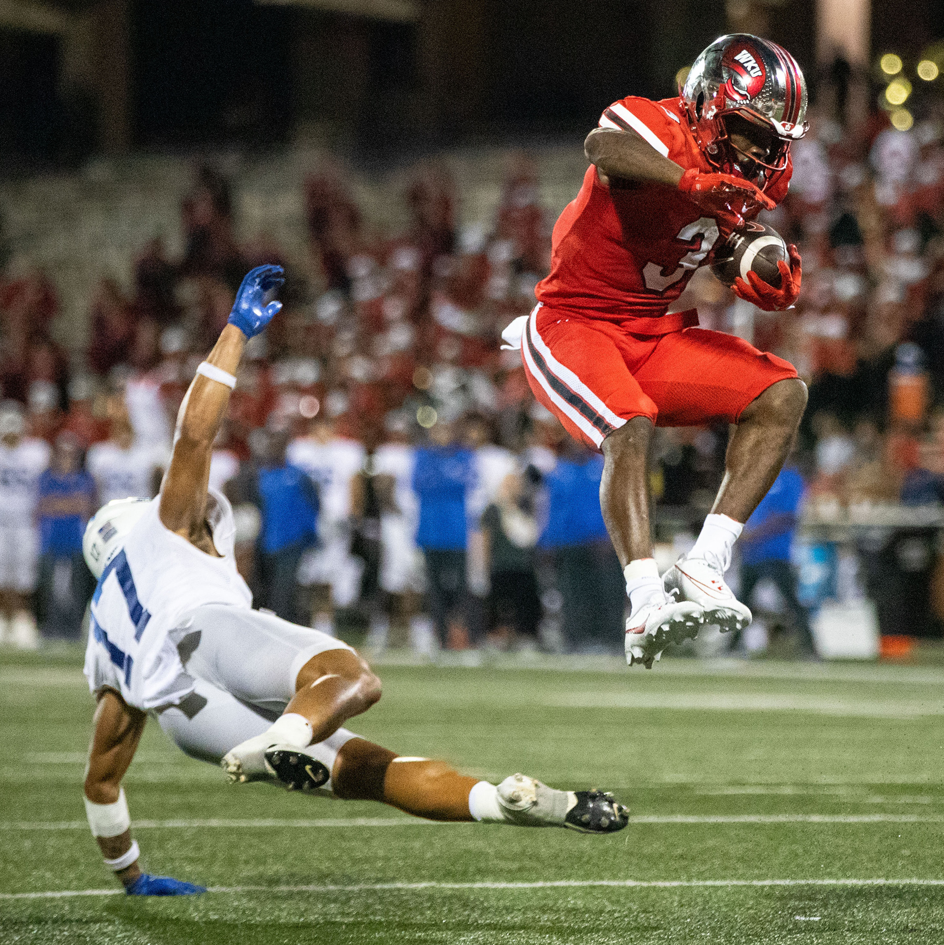 Western Kentucky University running back Elijah Young (3) jumps over Middle Tennessee State University safety Tra Fluellen to score a touch down during a home game at L.T Smith Stadium in Bowling Green, Ky. on Thursday, Sept. 28, 2023. 