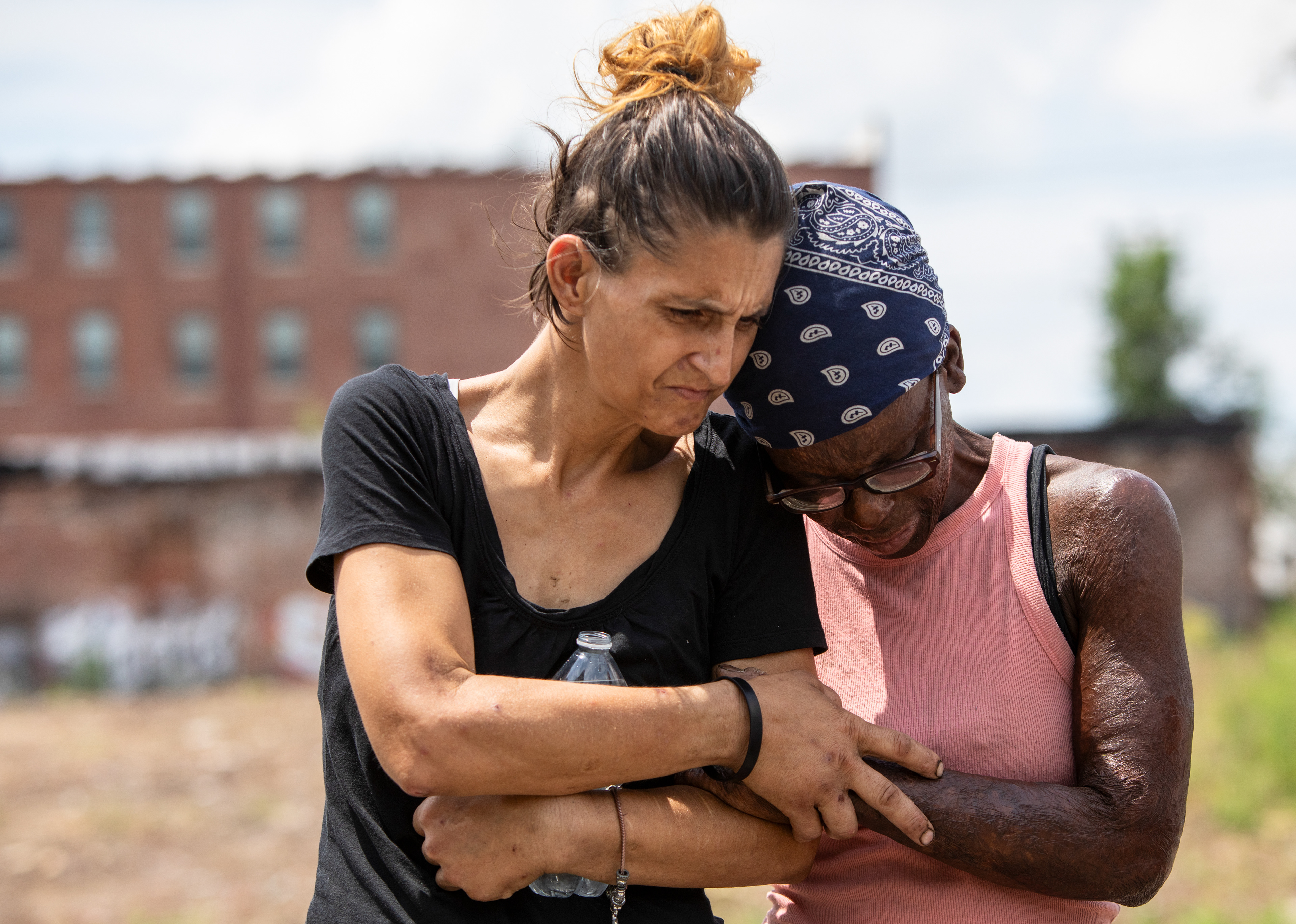 Jamie Mueller (left), who's been homeless for around six months, and Corinthians Robinson, who's been homeless for almost five months, embrace during a memorial service for their friend John Paul "JP" Yarborough hosted by New Life Evangelistic Center on the train tracks where he was struck at the intersection of Florida Street and North 1st Street in St. Louis, Mo. on Wednesday, July 17, 2024. Mueller claimed to have been the first person to find his body earlier that week. "I knew he was was struggling," Mueller said. "I definitely did. As we all are." 