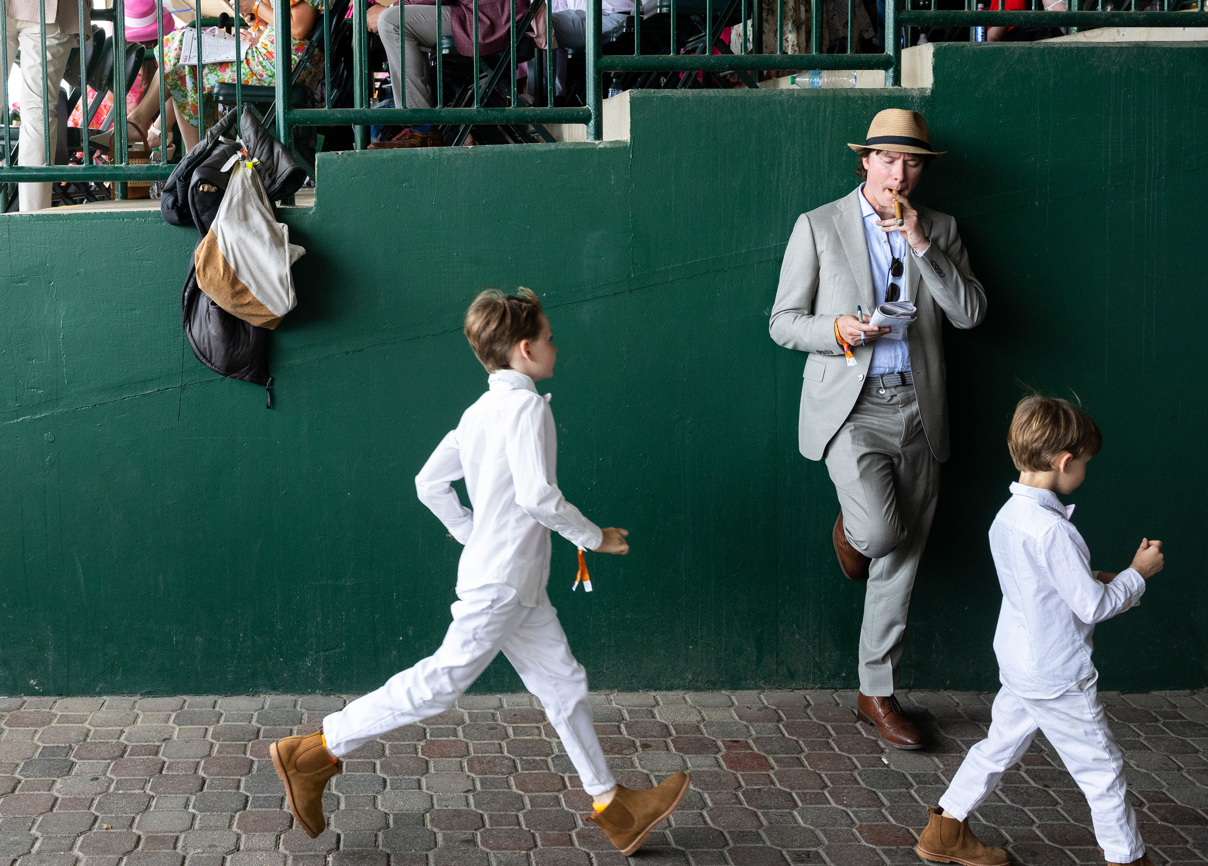 Drew Breese of Ohio smokes a cigar while checking out the Kentucky Oaks official program on the day of the 151st running of the Kentucky Oaks horse at Churchill Downs in Louisville, Ky. on Friday, May 2, 2025. Breese came to Churchill Downs on a boys' trip with his friends from around the country. 