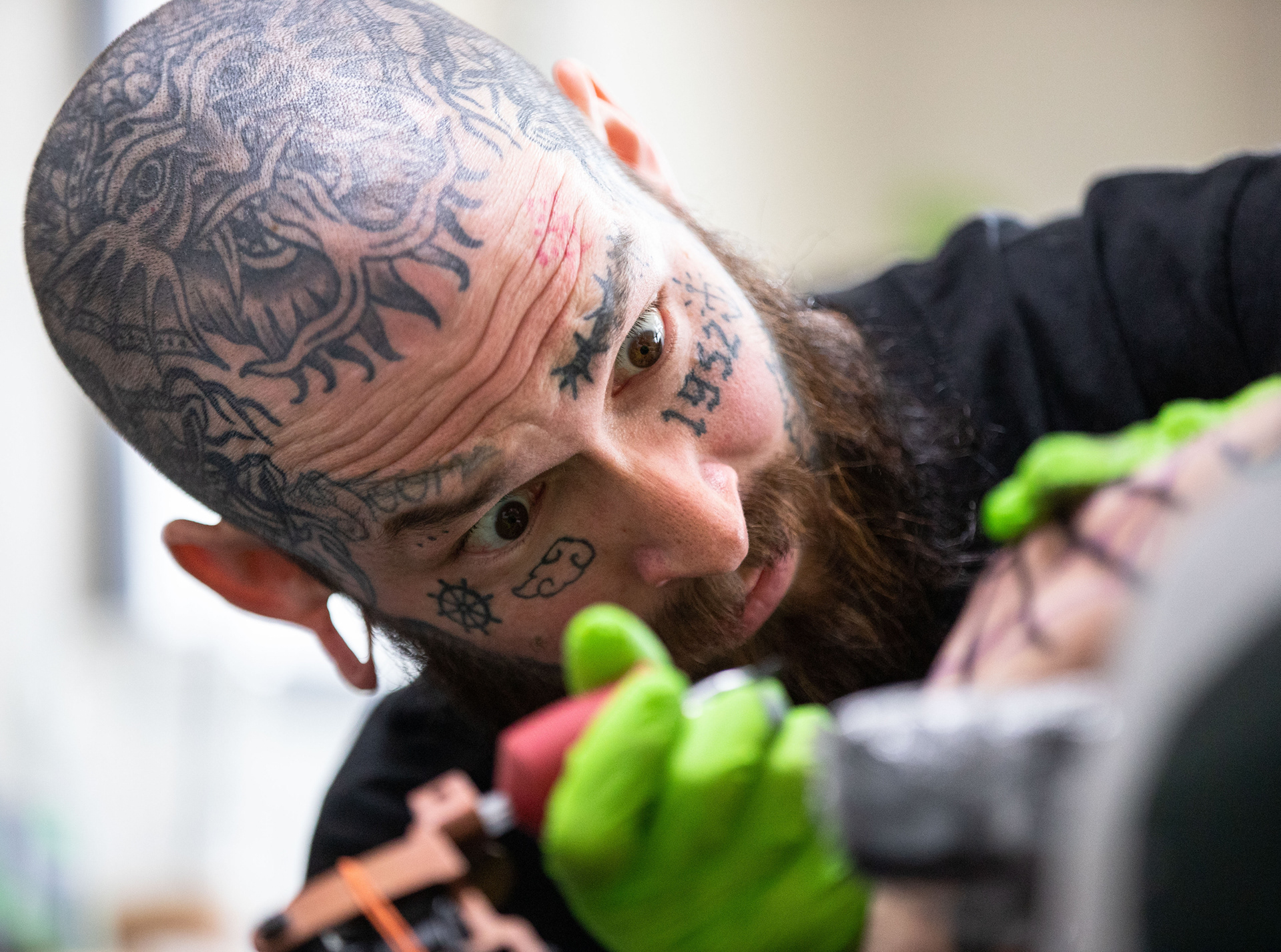 Mike Woods looks at a spider web tattoo in confusion at The Crawling Panther Tattoo Company in Bowling Green, Ky. on Friday, April 5, 2024. It was Woods’ first time tattooing an elbow and tattooing something without a stencil. "I want everybody to have a good tattoo," Woods said. “Because I mean, I know how important this s*** is. And so I was basically just kind of just a nervous wreck the whole time."