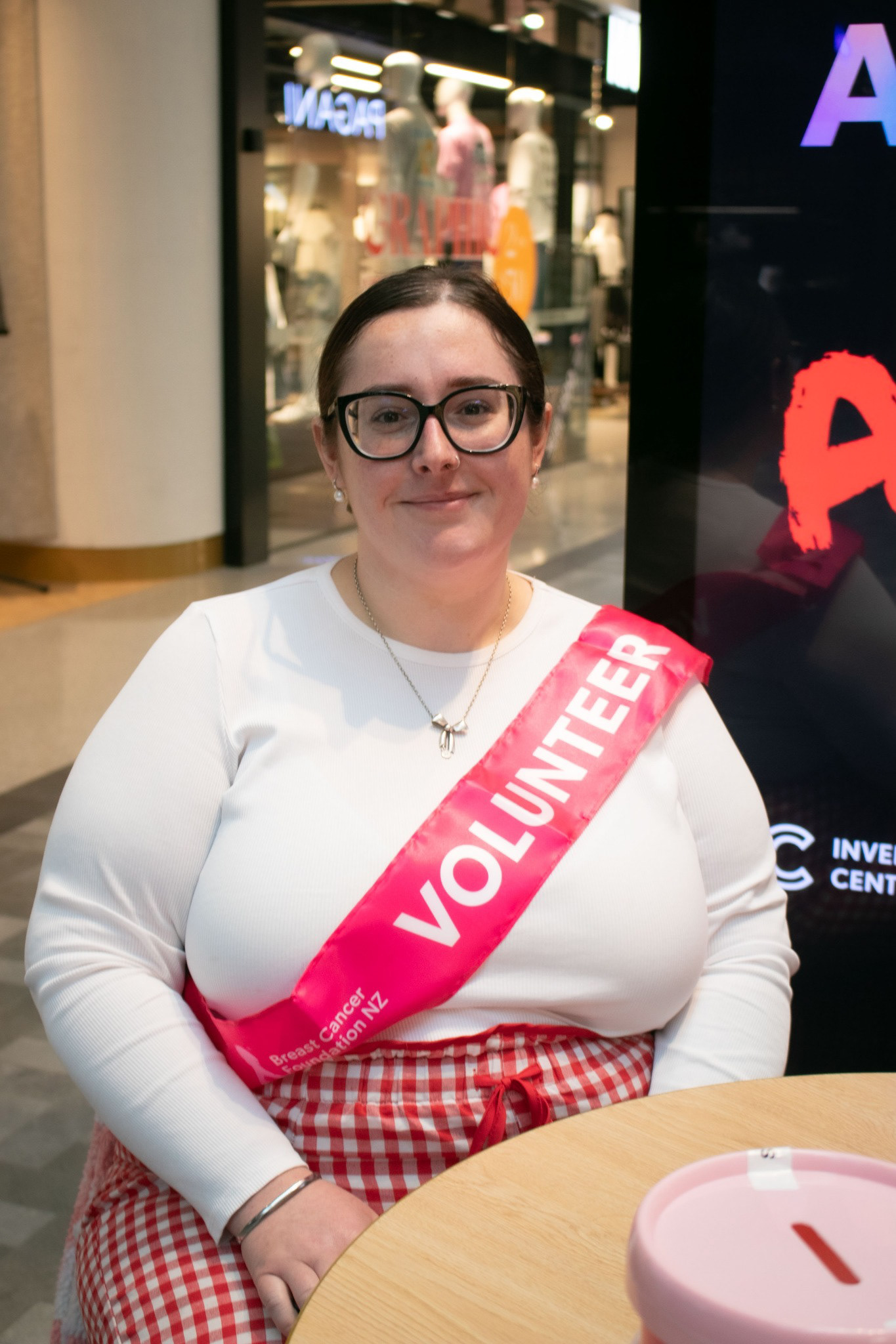Bayley McKeown volunteering at a Breast Cancer Foundation fundraiser, sitting behind a table.